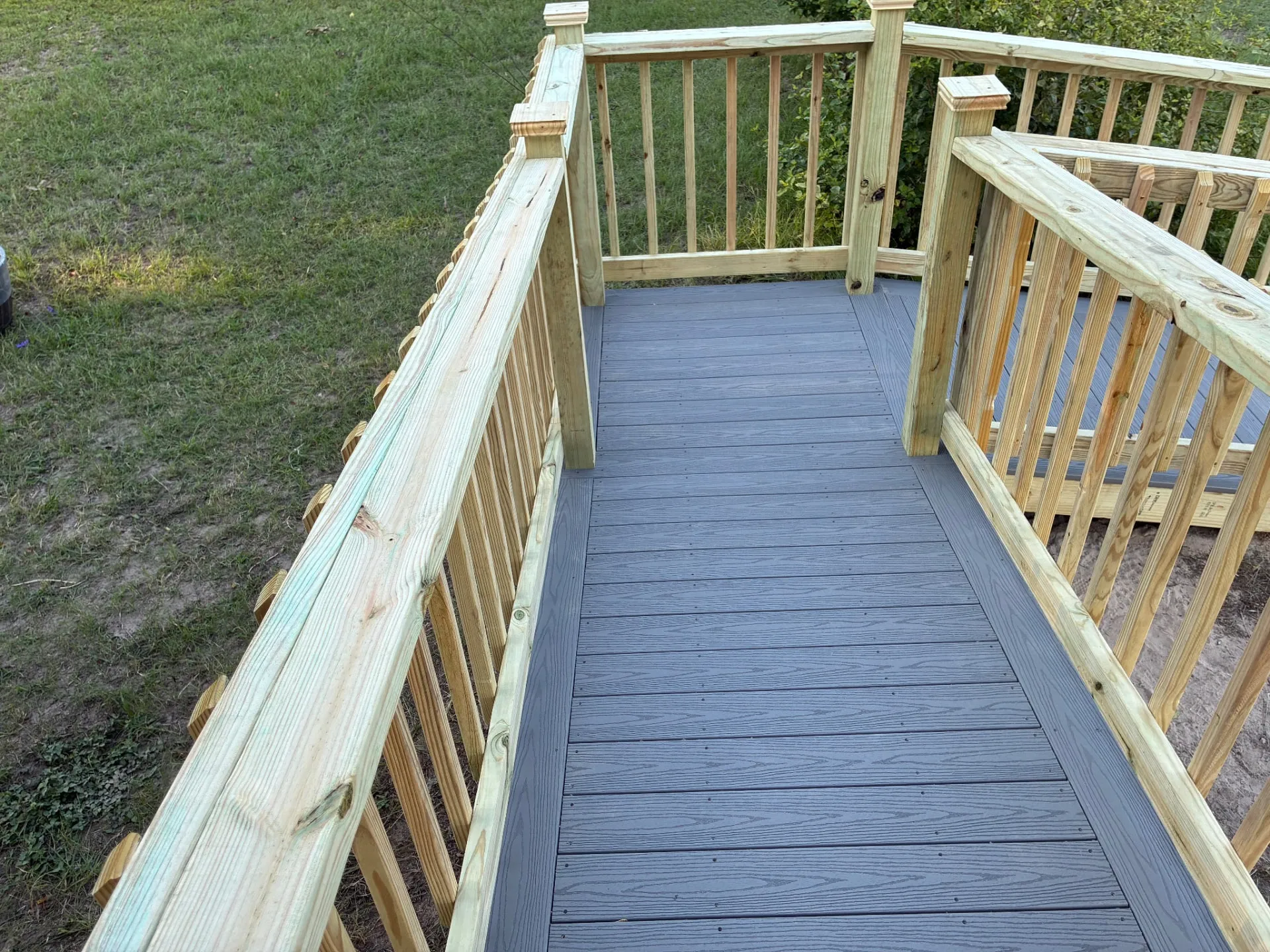 Composite ramp landing with treated wood spindle railing, built by BenchMark Decks in Trinity, Texas
