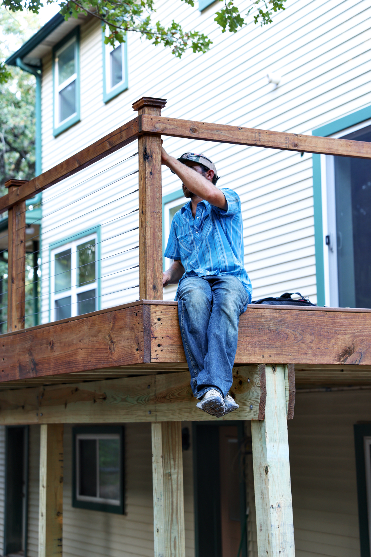 Benchmark Decks crew member installing cable railing on an elevated deck in Grandview, TX