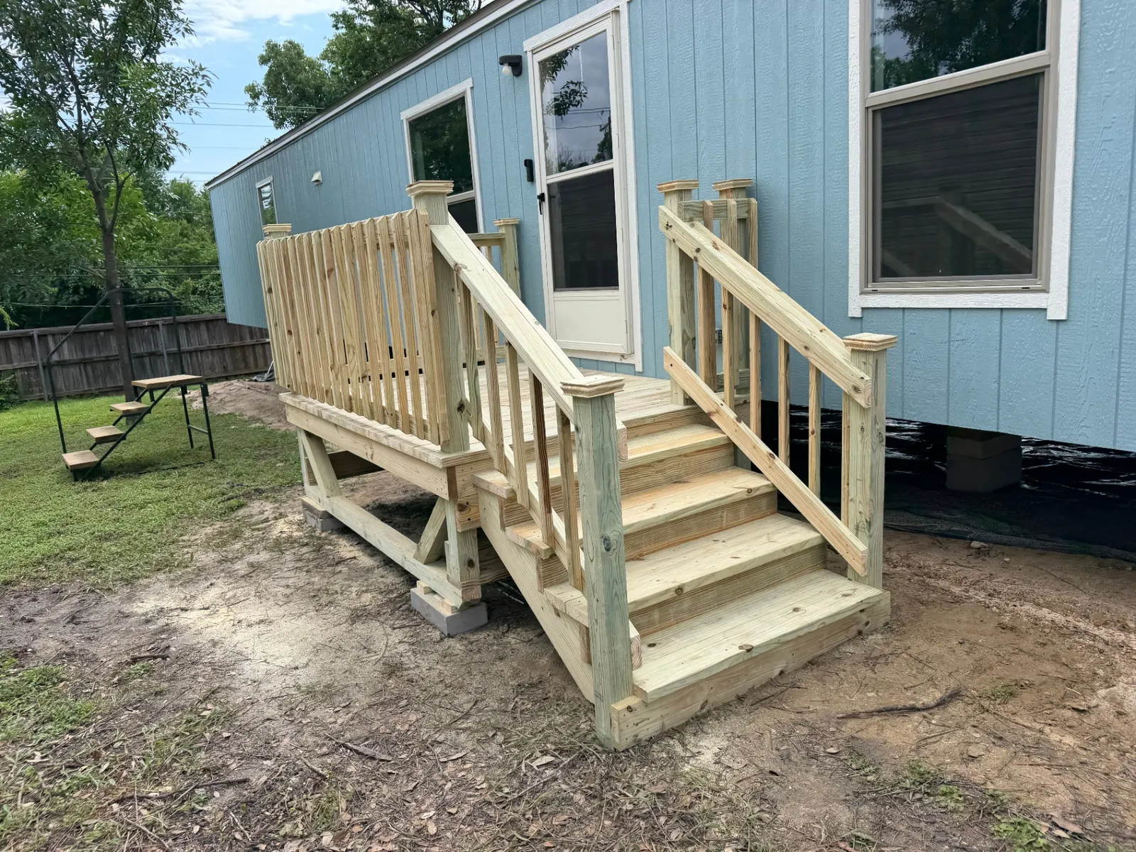 4x4 pressure treated entry deck with steps and wood railing on a manufactured home, built by BenchMark Decks in Dallas, Texas