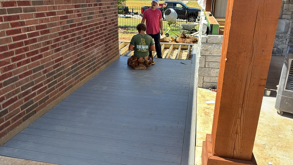 Gray composite decking mostly installed on Chase's deck beside the brick wall
