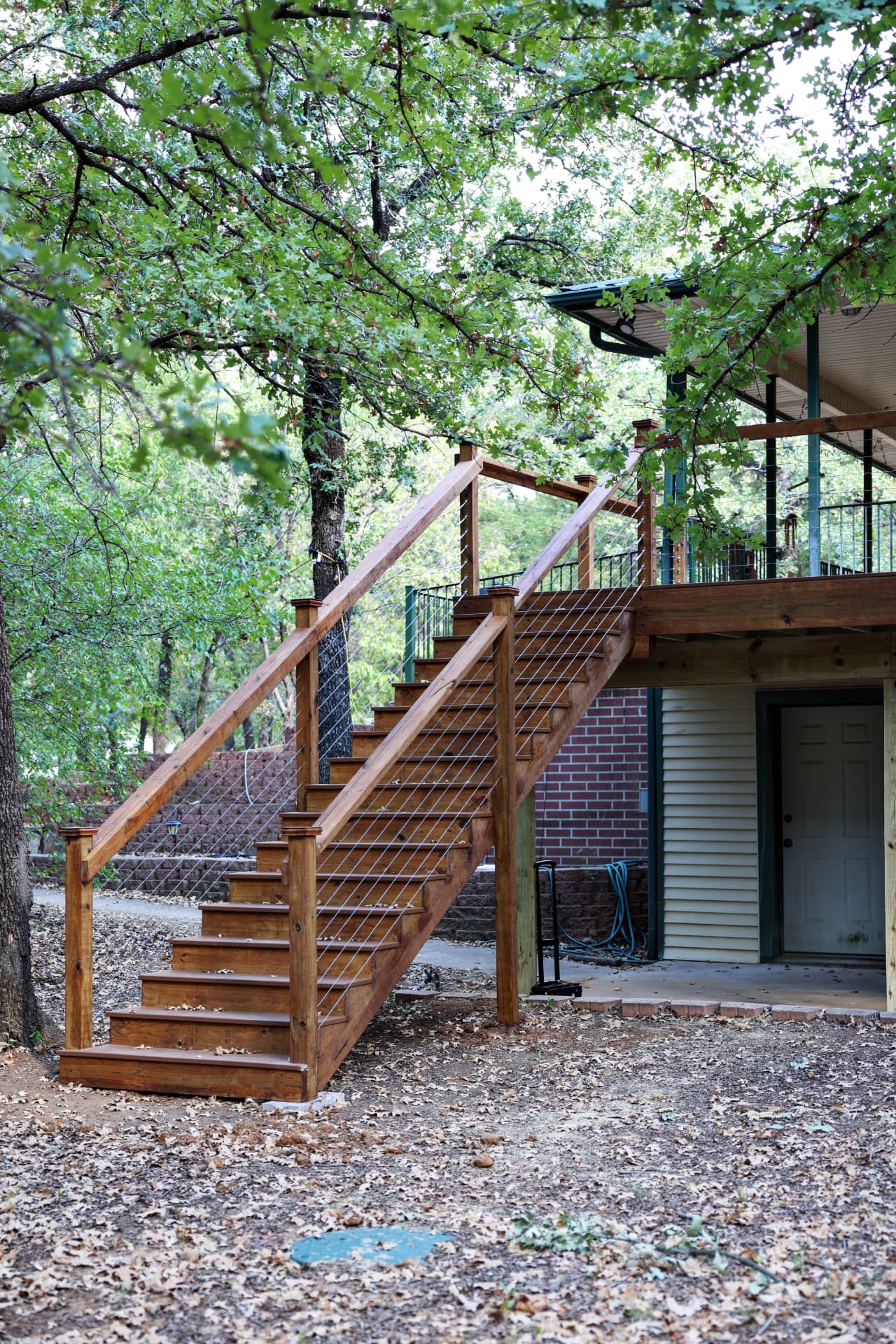 Stained wood stair run with cable railing leading down to grade