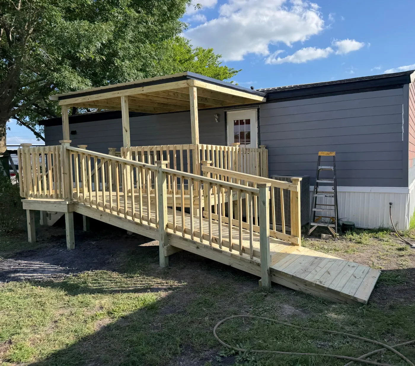 Covered mobile home deck with a long ADA-style access ramp and railing
