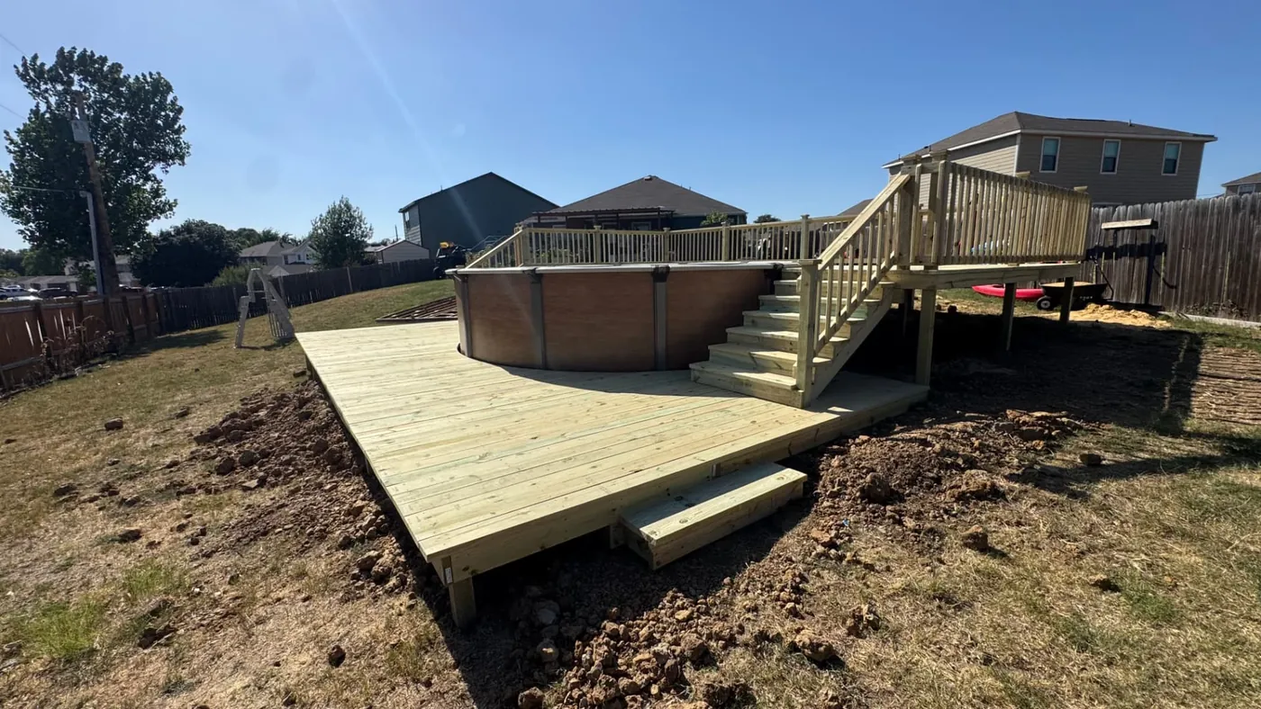 Ground-level pool deck wrapping an above-ground pool with elevated stair landing