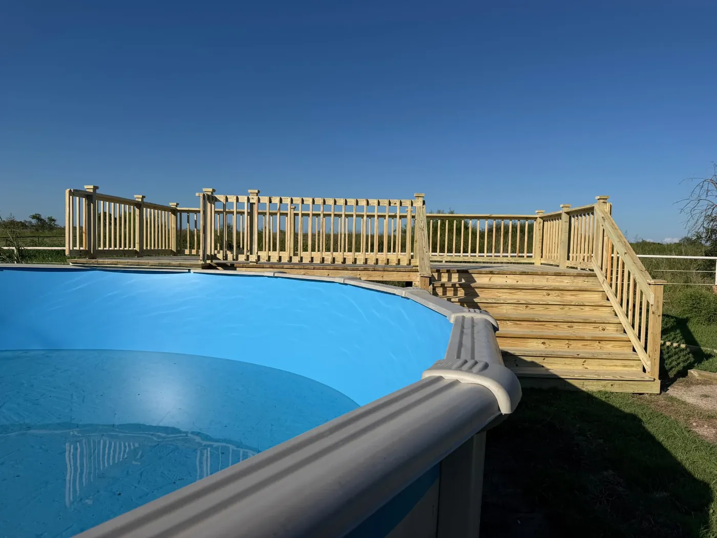 Wrap-around above-ground pool deck with railing and stairs
