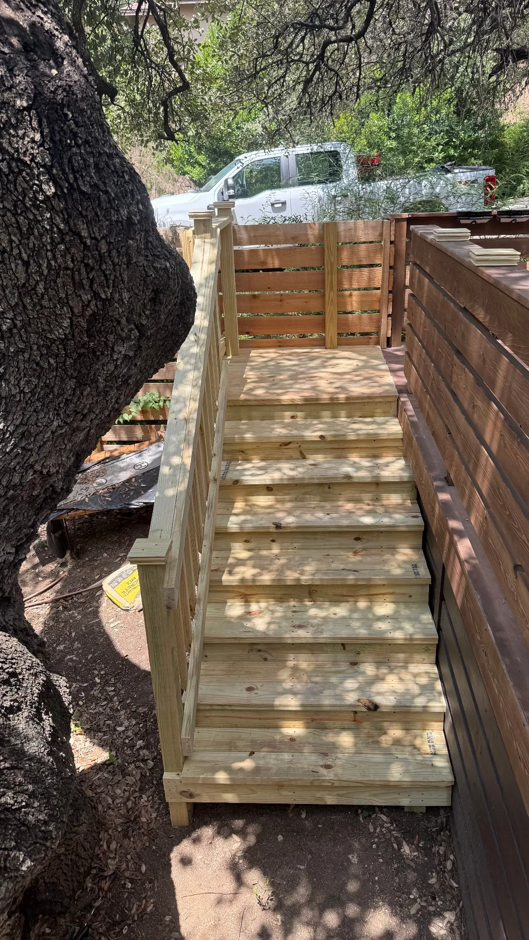 4 foot wide pressure treated steps with wood railing and post caps leading to a 4x4 landing, built by BenchMark Decks in Austin, Texas