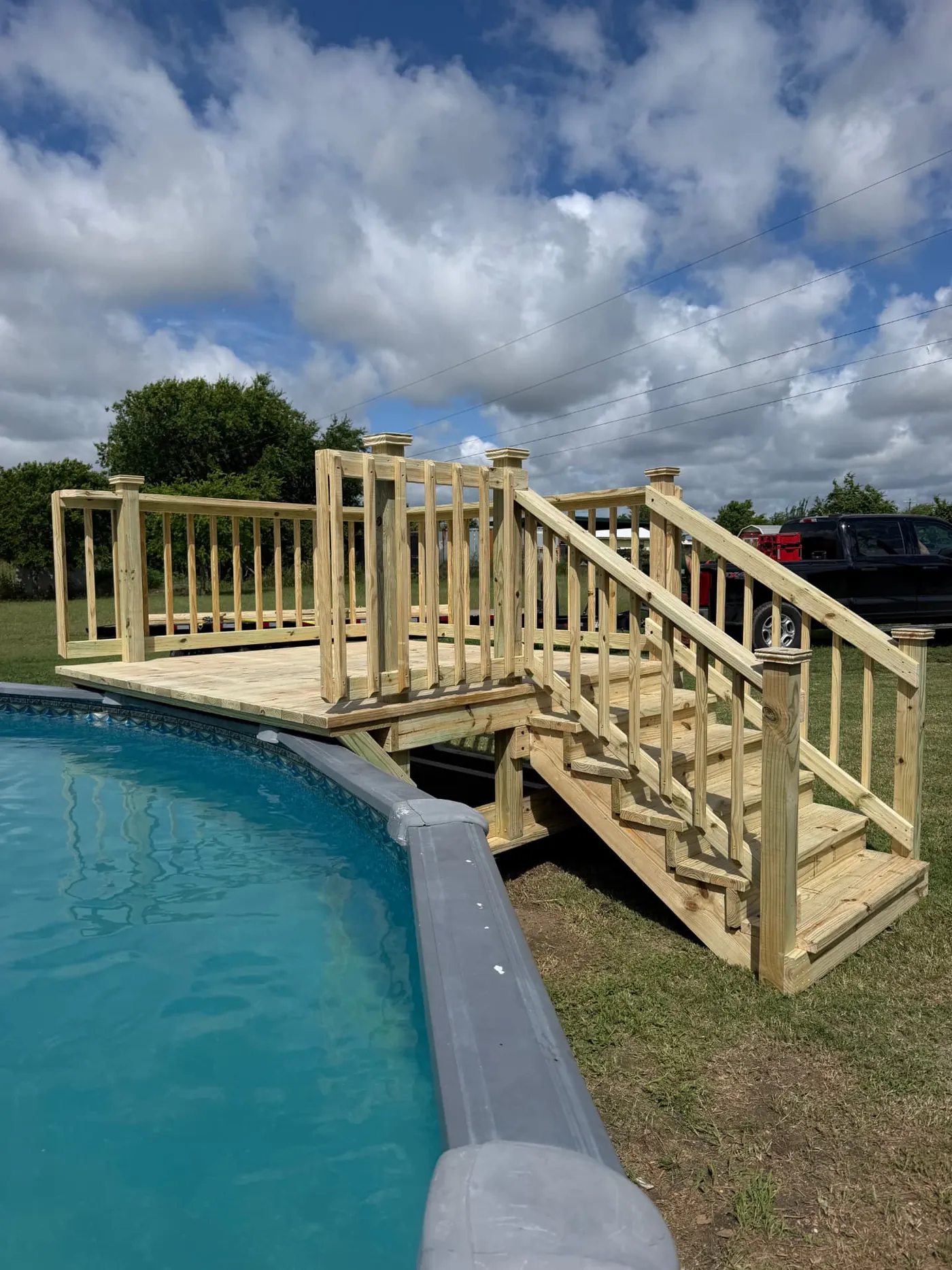 Pool deck landing with railing and stairs next to an above-ground pool