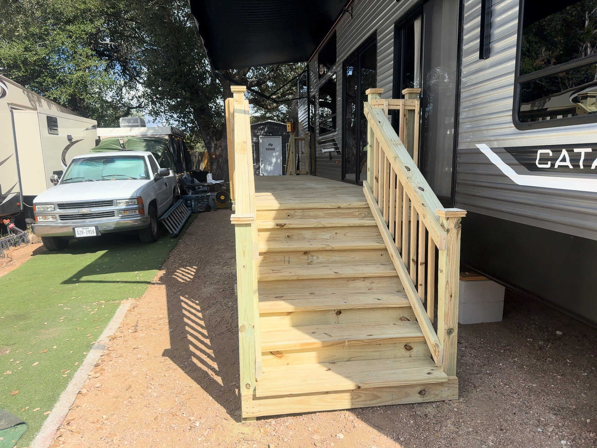 Pressure treated stairs with wood handrail leading up to an RV deck