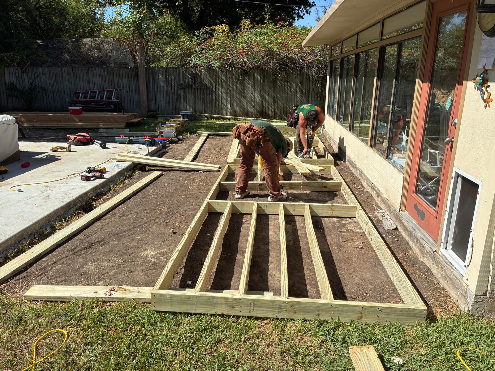 Crew building the pressure treated deck frame along the back of Danny's house