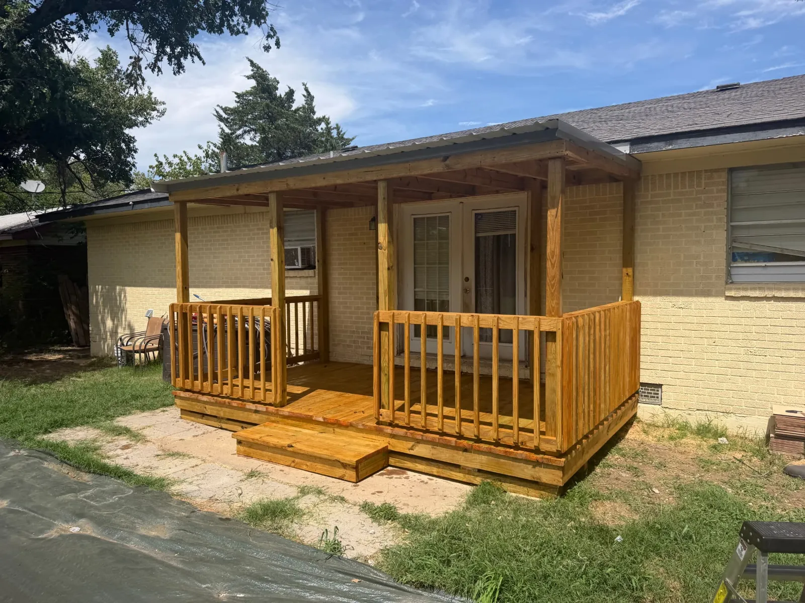 8x14 pressure treated deck with natural cedar stain, pewter gray single slope metal roof and centered steps, built by BenchMark Decks in Lawton, Oklahoma