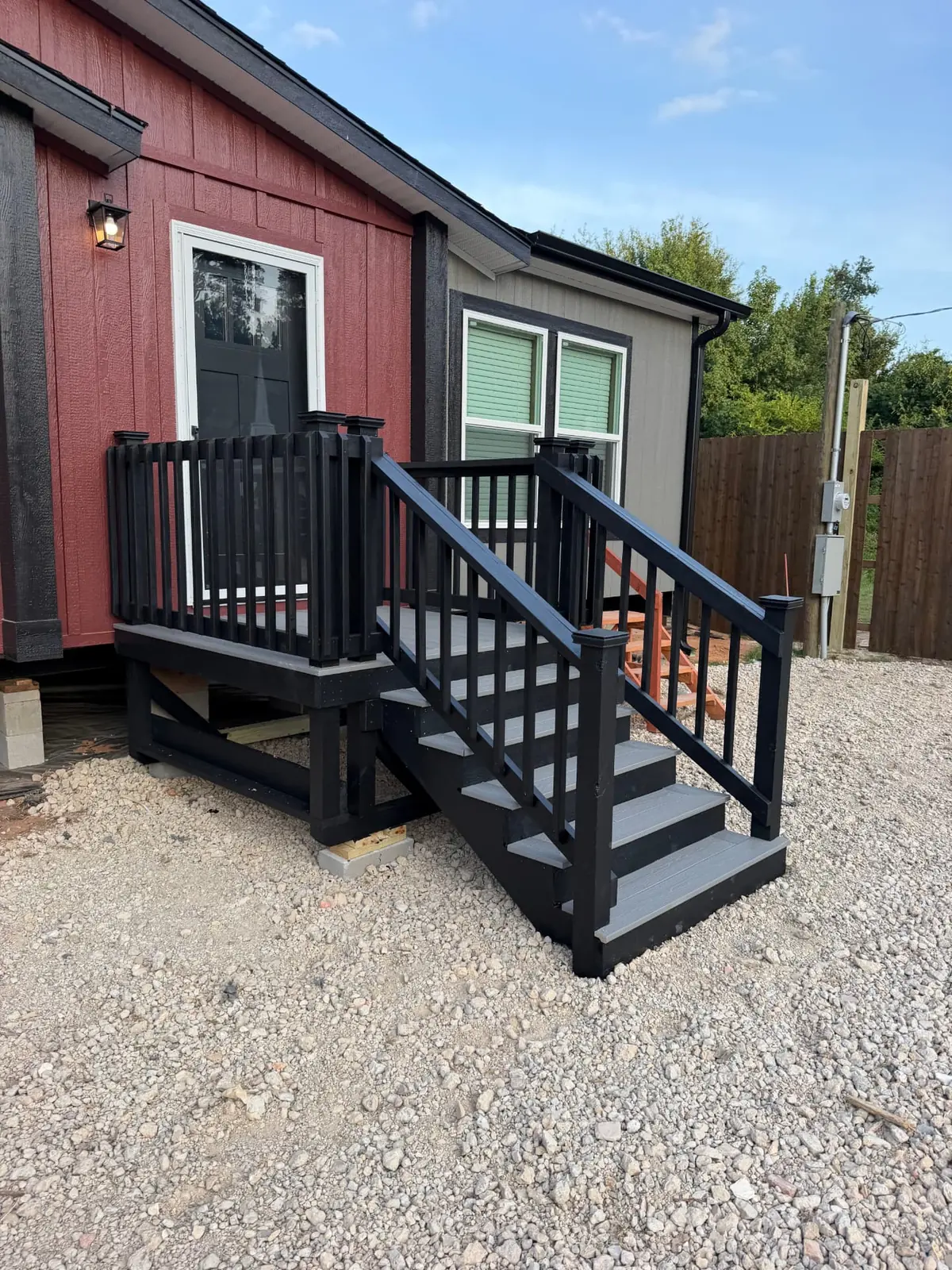 Black-stained entry deck with gray composite decking and stairs