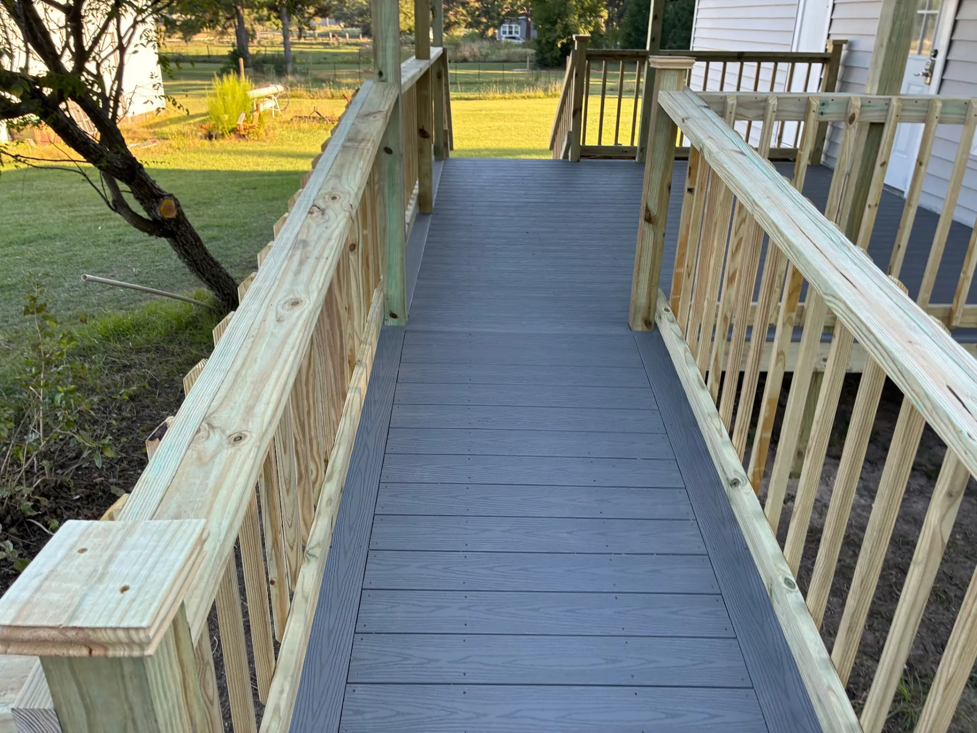 Composite ramp with treated wood handrails leading to the main deck, built by BenchMark Decks in Trinity, Texas