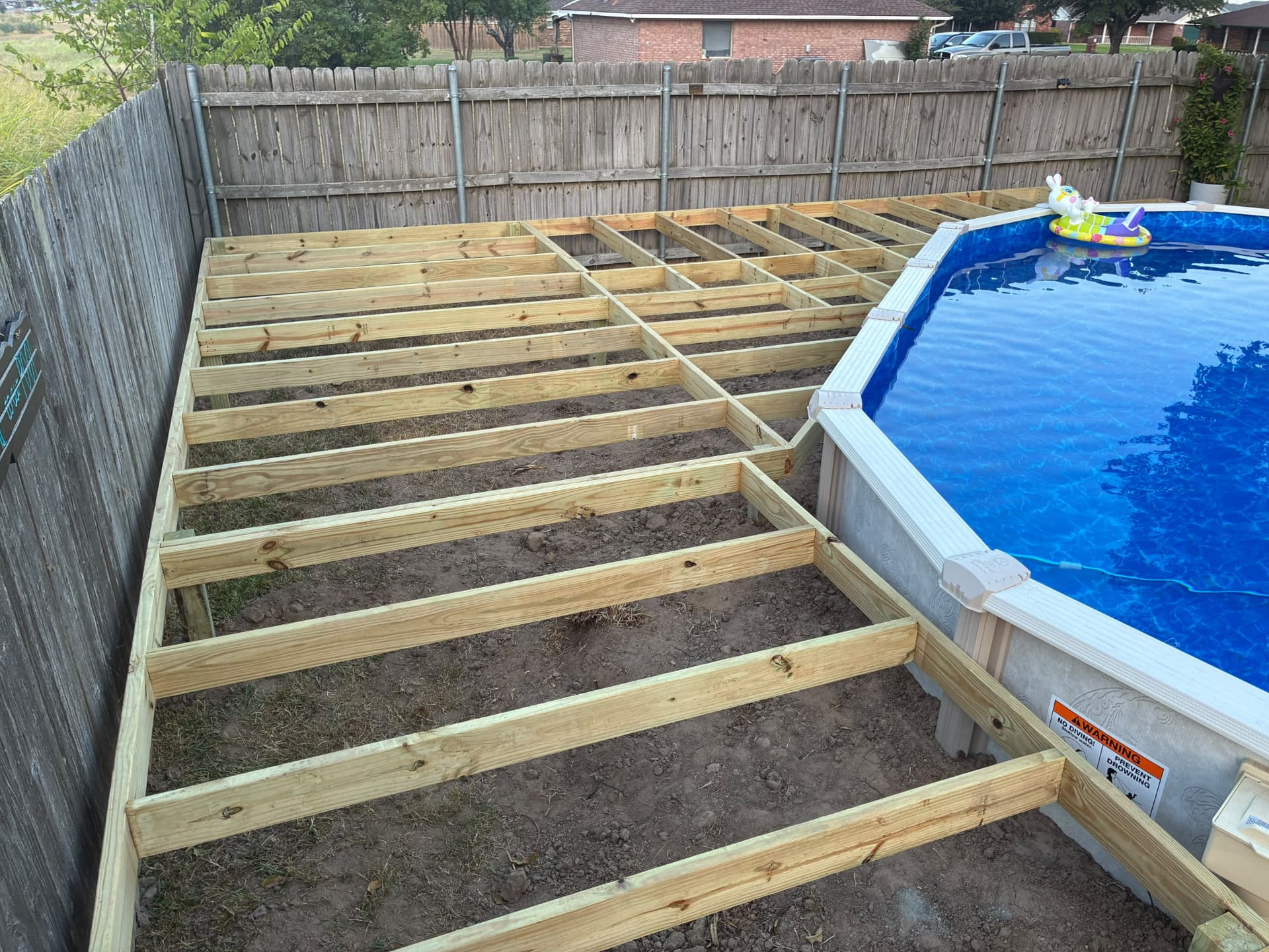 Deck framing running along the fence line next to Terri's pool, built by BenchMark Decks in Mabank, Texas