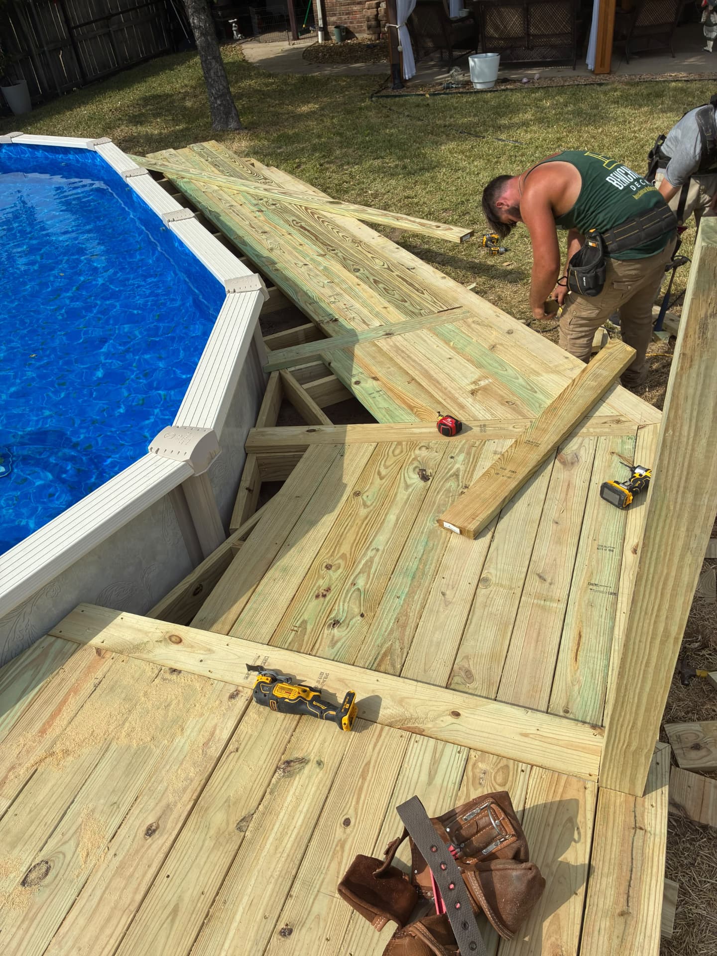 BenchMark crew laying pressure treated deck boards around Terri's above-ground pool, built by BenchMark Decks in Mabank, Texas