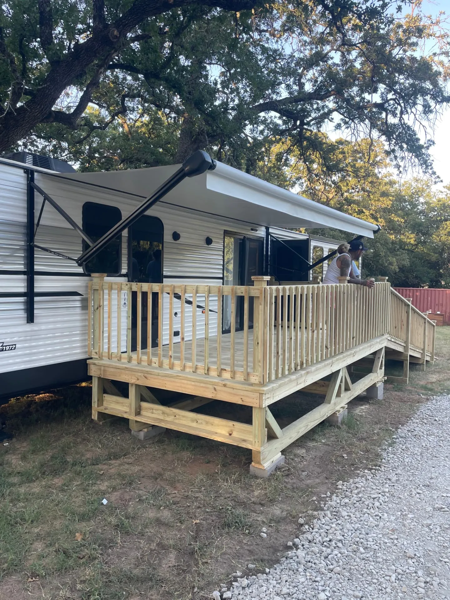 8x16 pressure treated RV deck with railing beside a travel trailer, built by BenchMark Decks in Weatherford, Texas