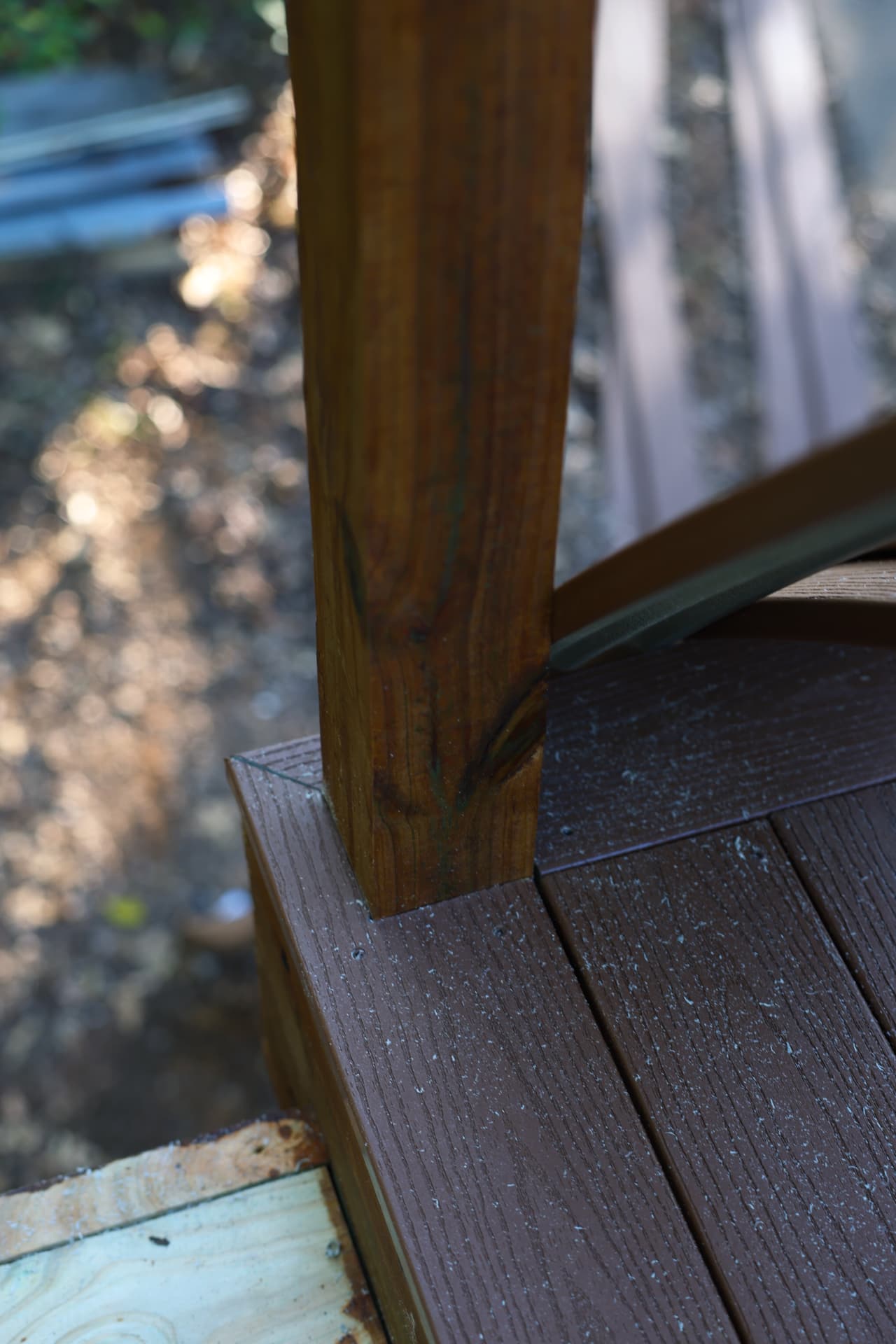 Composite deck board notched around a stained rail post with cable railing hardware
