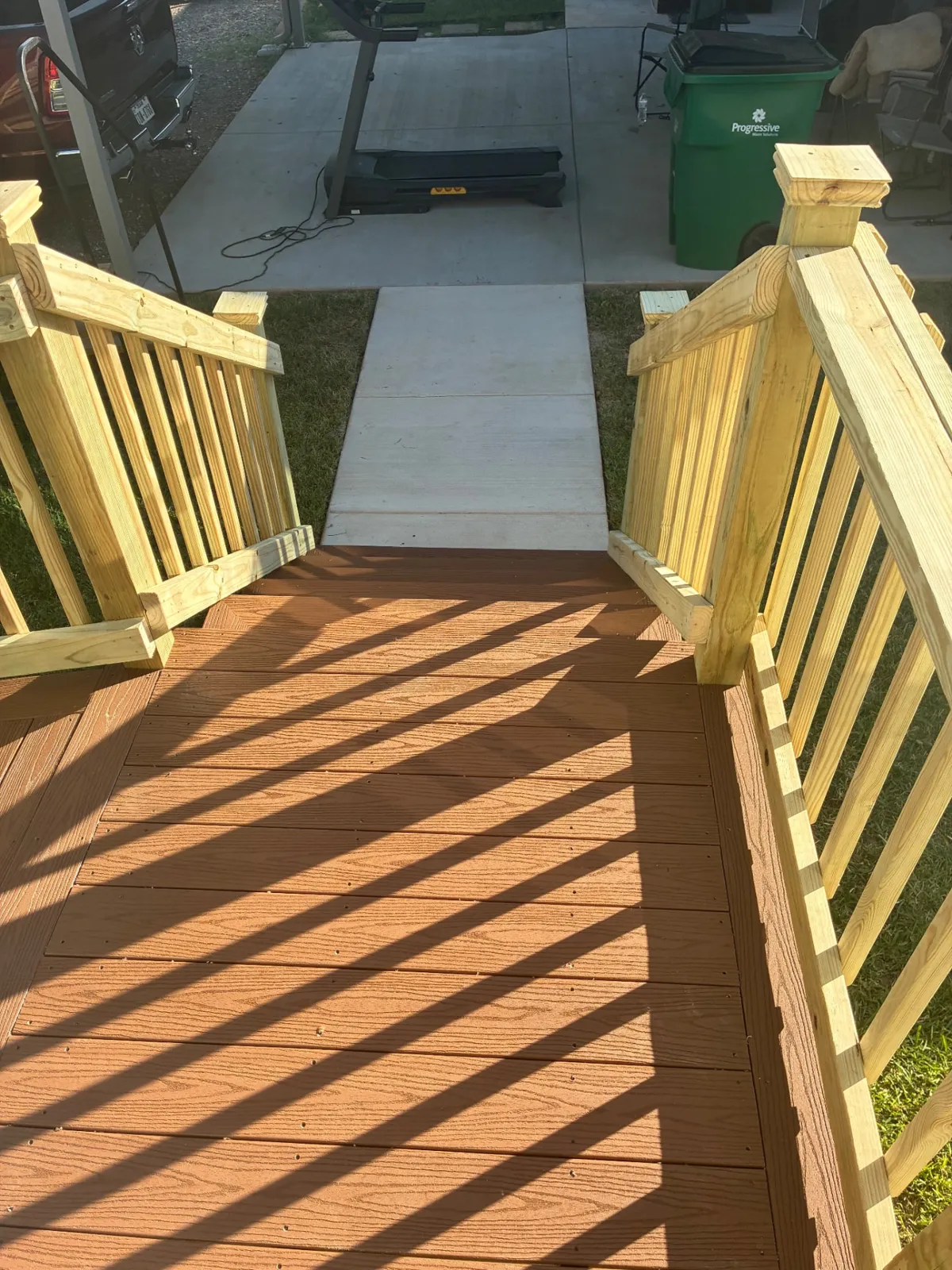 Cabin composite ramp with spindle railing leading to a sidewalk, built by BenchMark Decks in Fort Worth, Texas