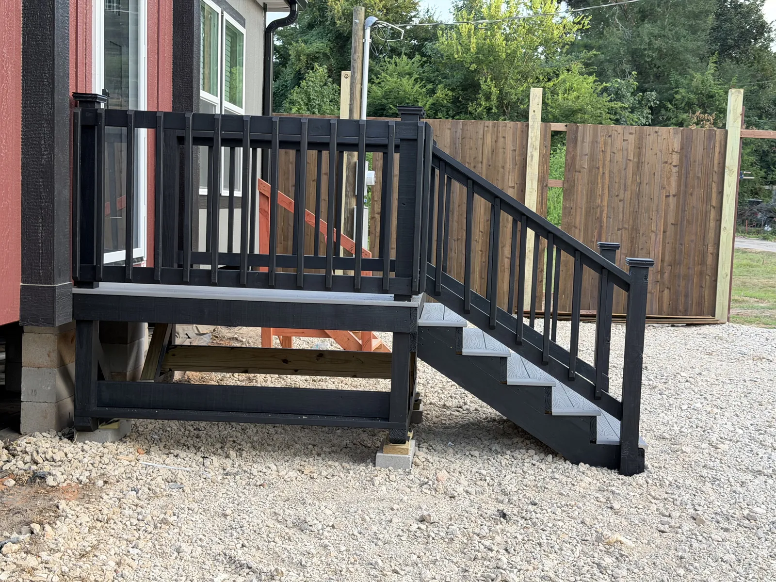 Black and gray side steps and landing with spindle railing on a new home, built by BenchMark Decks in Tyler, Texas