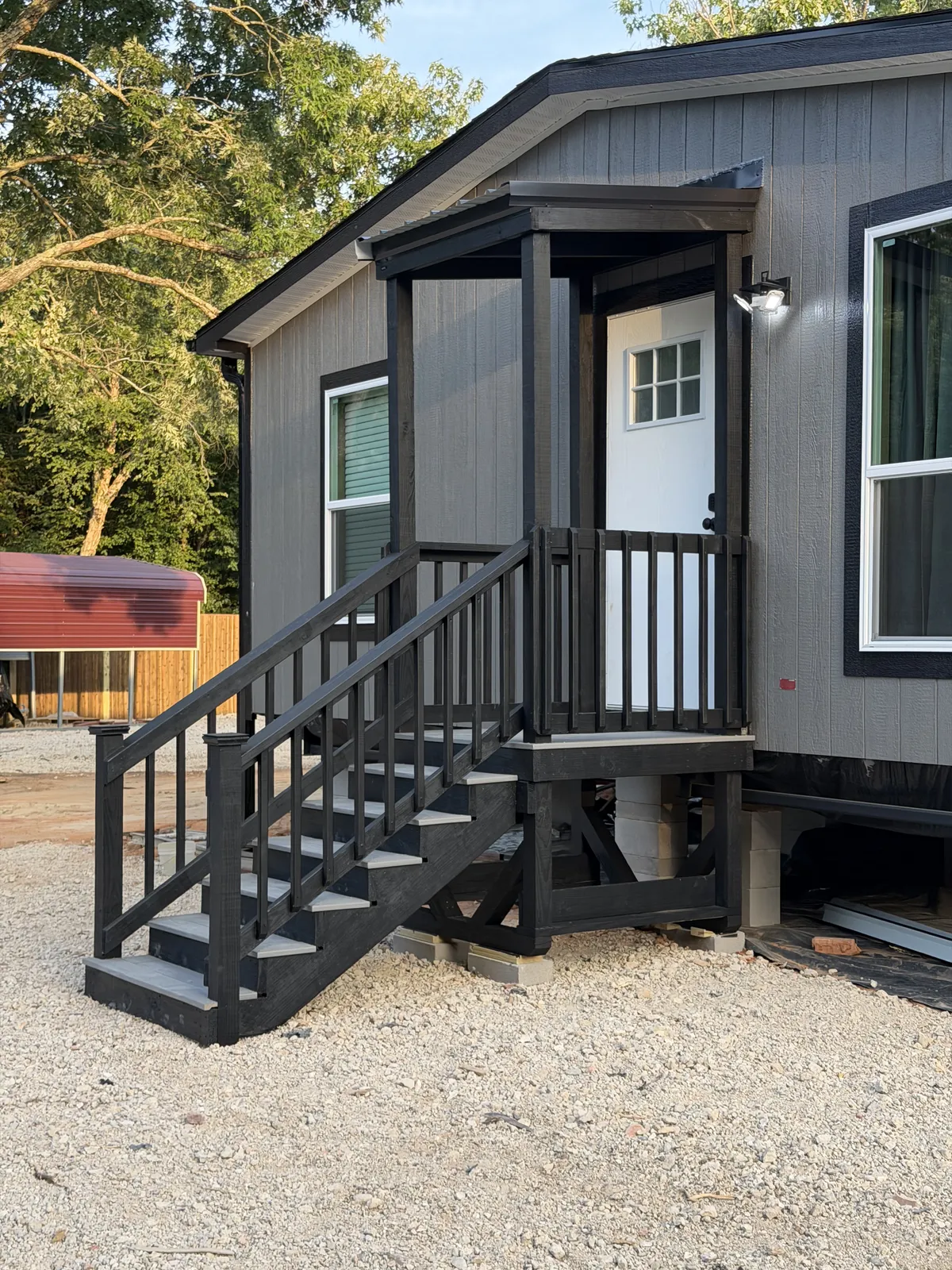 Black and gray covered entry landing with stairs and spindle railing on a new home, built by BenchMark Decks in Tyler, Texas