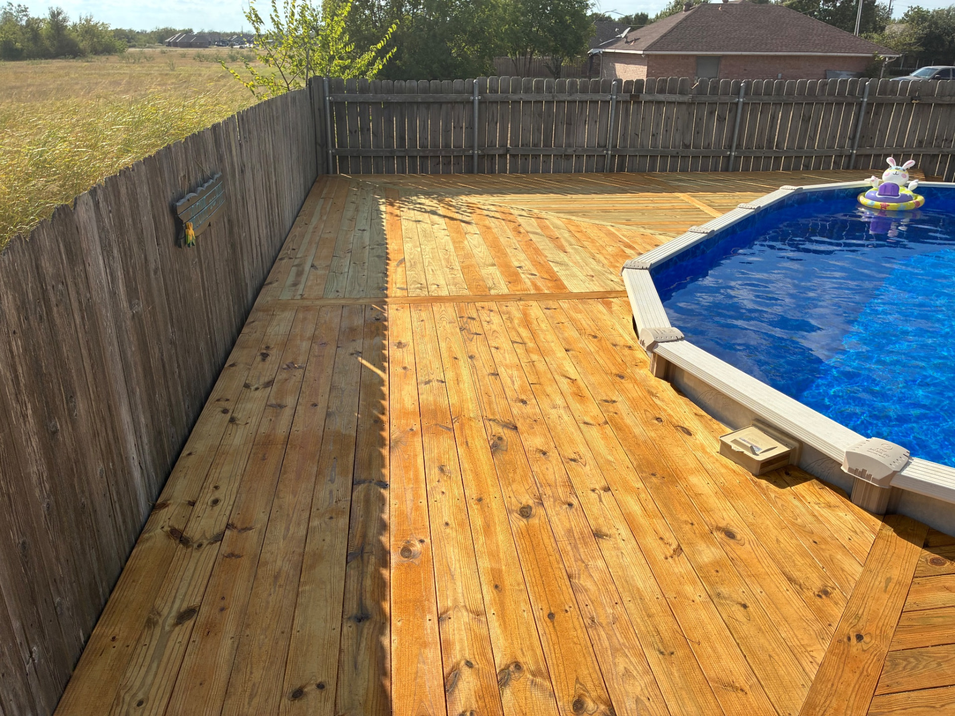 Finished stained deck along the fence beside Terri's above-ground pool, built by BenchMark Decks in Mabank, Texas