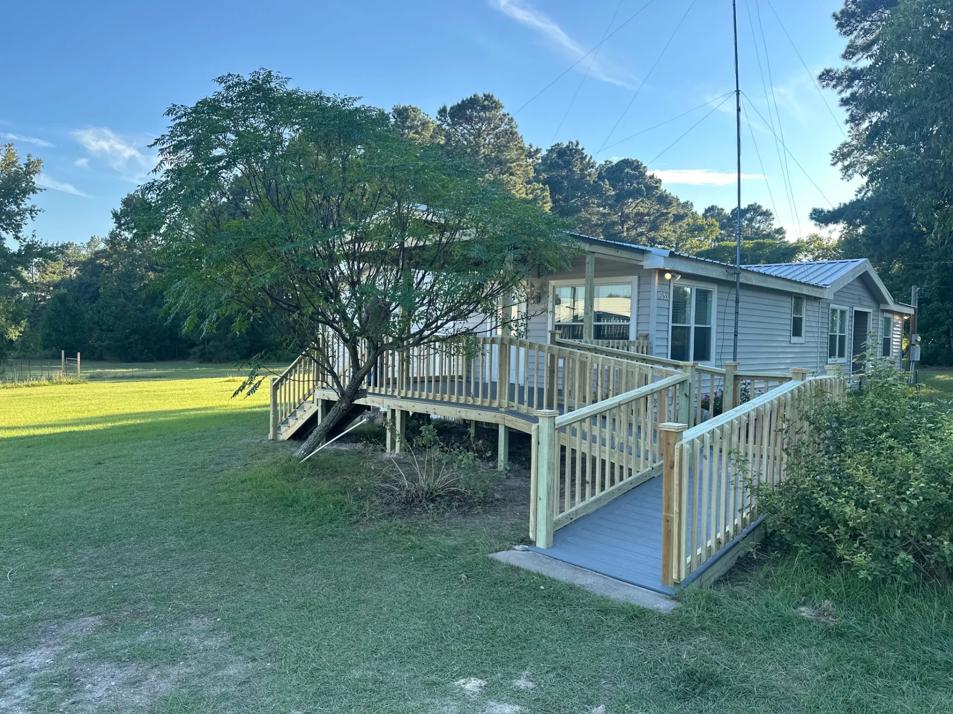 12x14 composite deck with treated wood railing and a ramp leading to a concrete pad, built by BenchMark Decks in Trinity, Texas