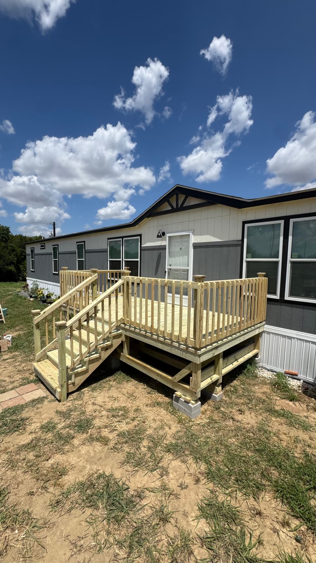 Freestanding pressure-treated deck with railing and stairs at a manufactured home