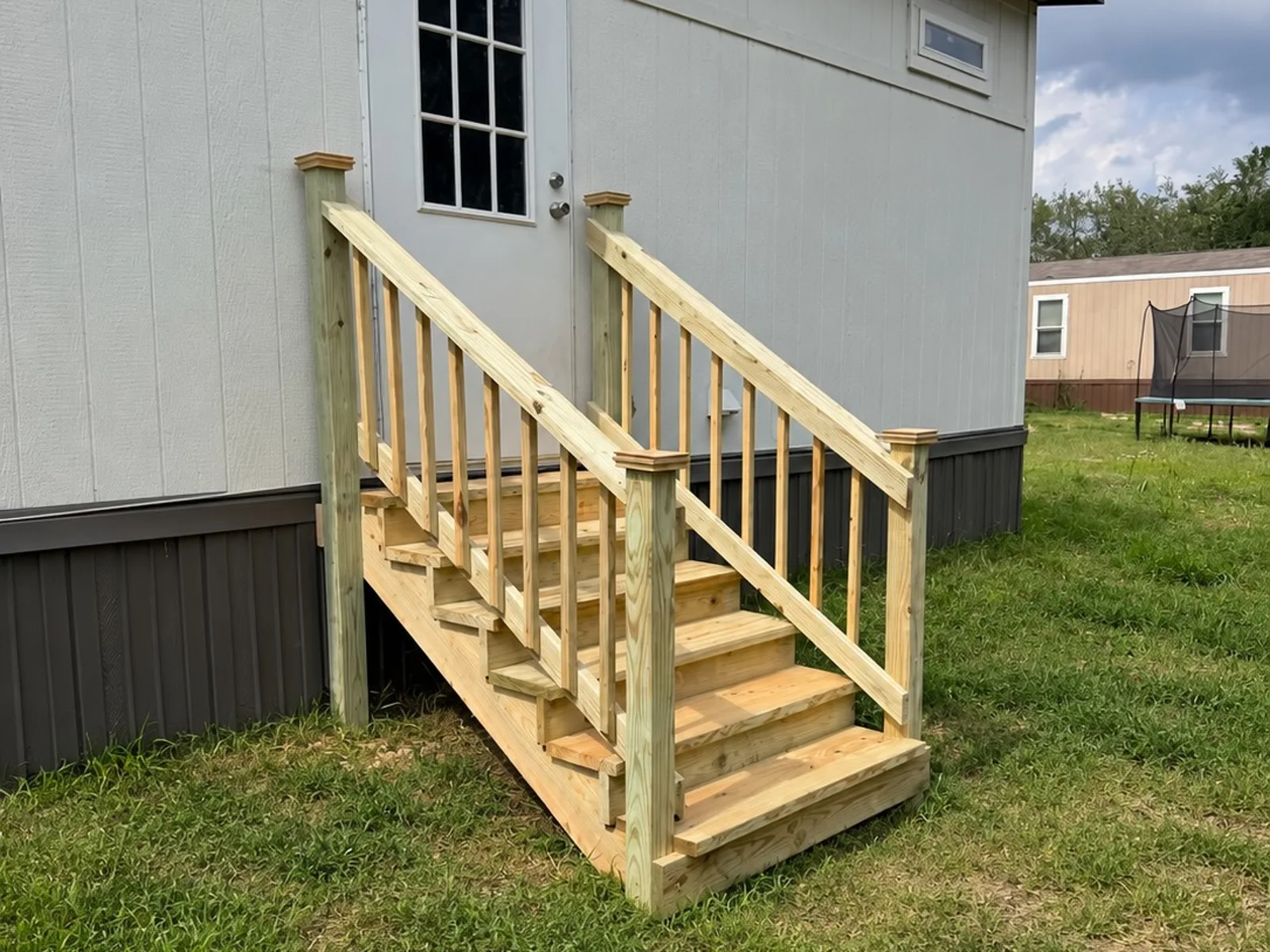 Wood entry steps with spindle railings and post caps on a mobile home, built by BenchMark Decks