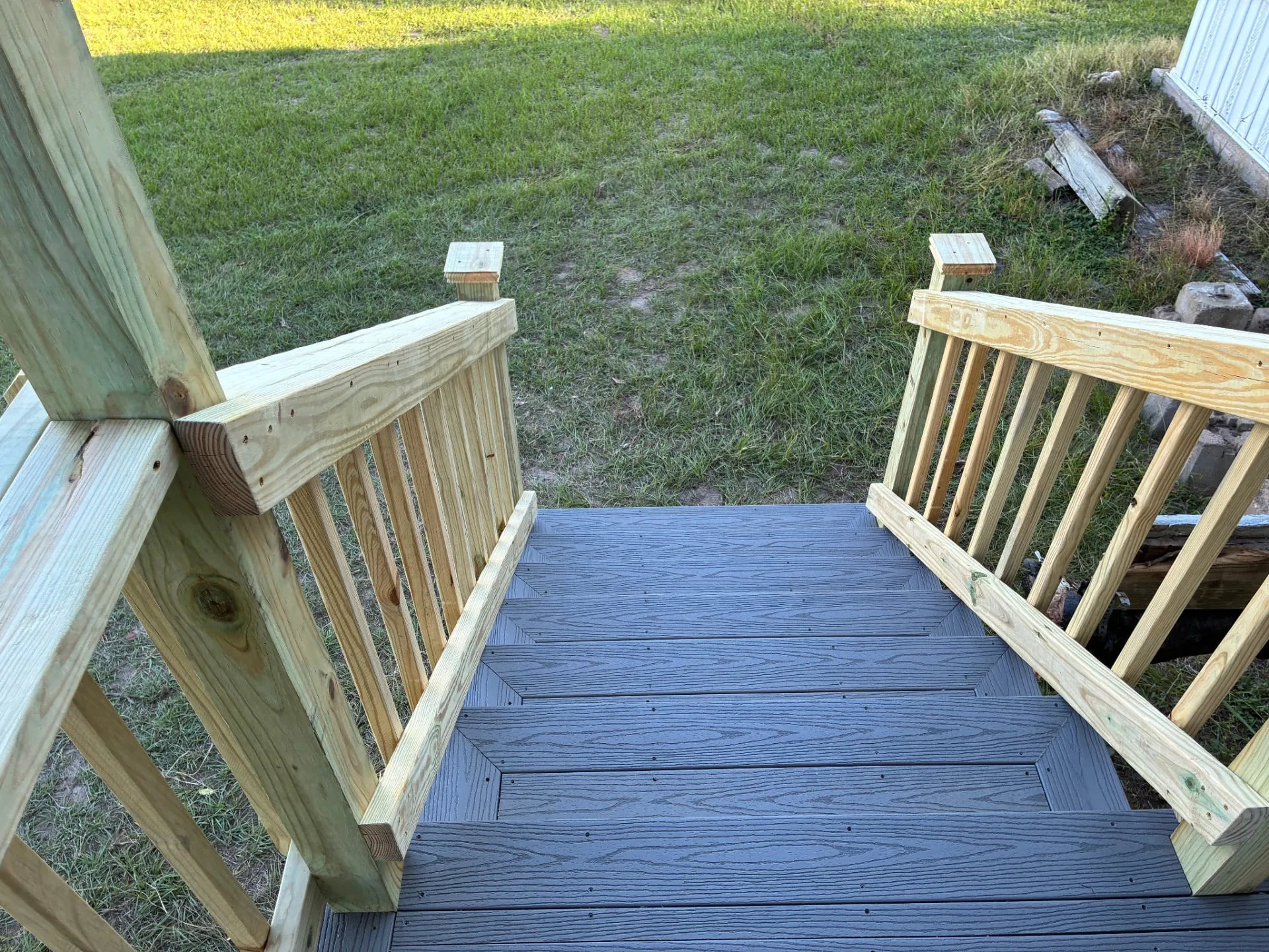 Composite steps with treated wood handrails off the side of the deck, built by BenchMark Decks in Trinity, Texas
