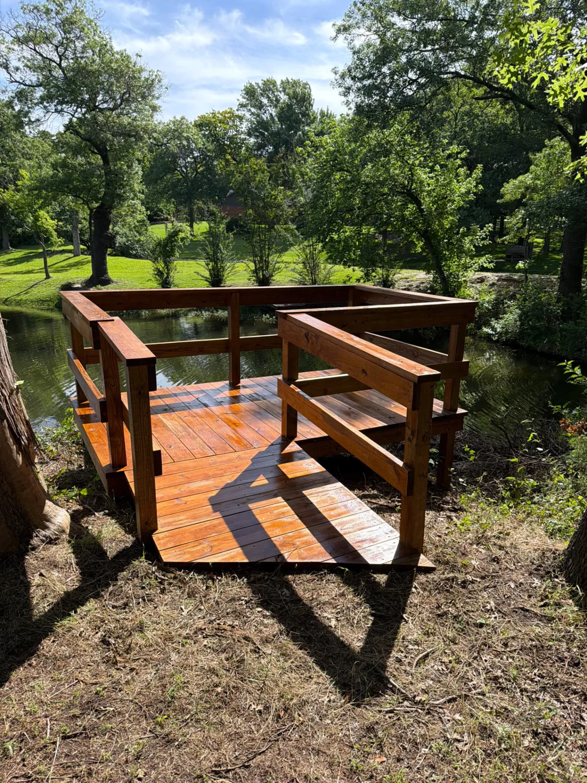 Dark walnut stained pond deck with 4x5 ramp and 2x6 railing, built by BenchMark Decks in Weatherford, Texas