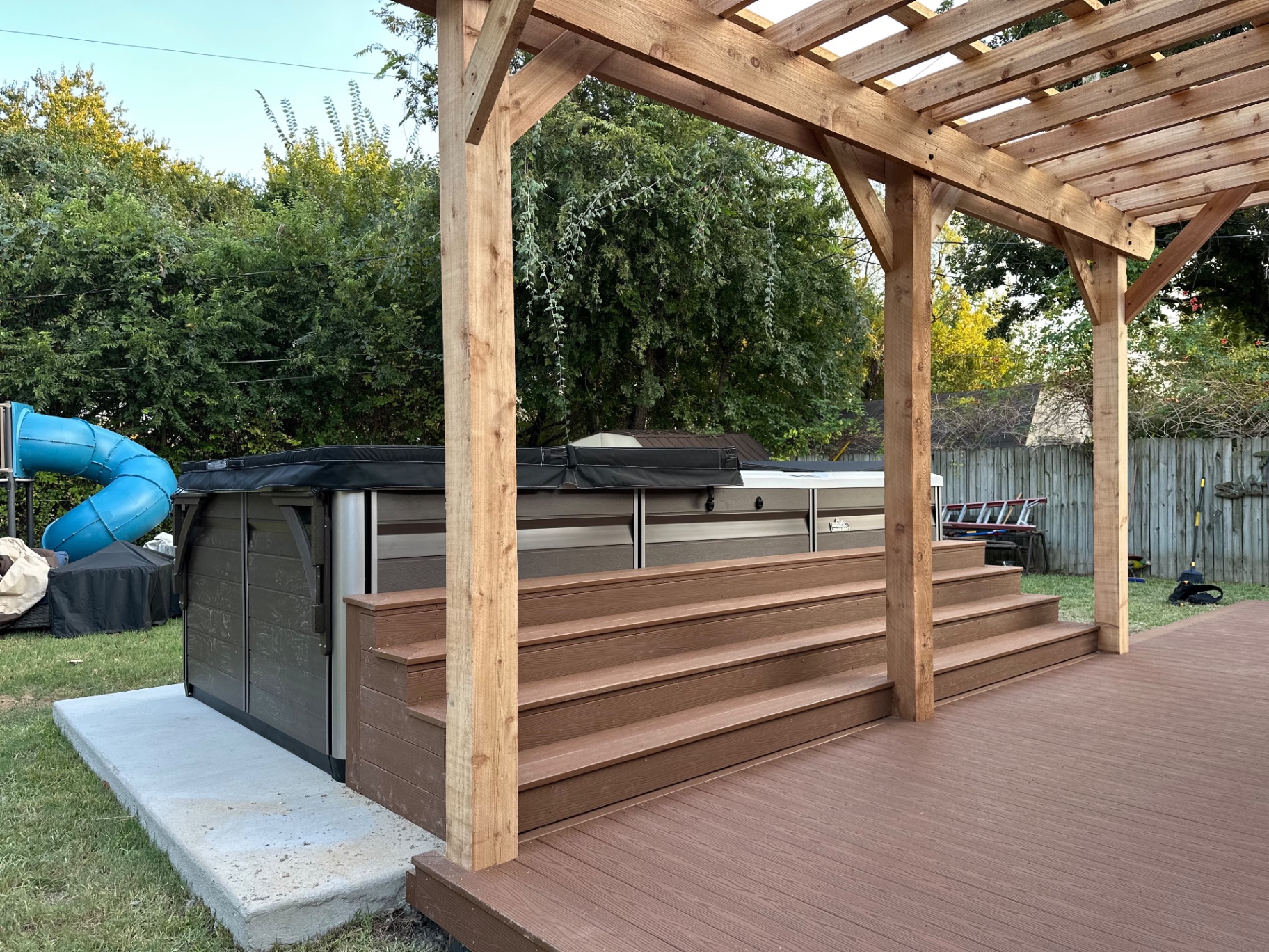 Wide composite steps leading up to the pool spa under Danny's cedar pergola
