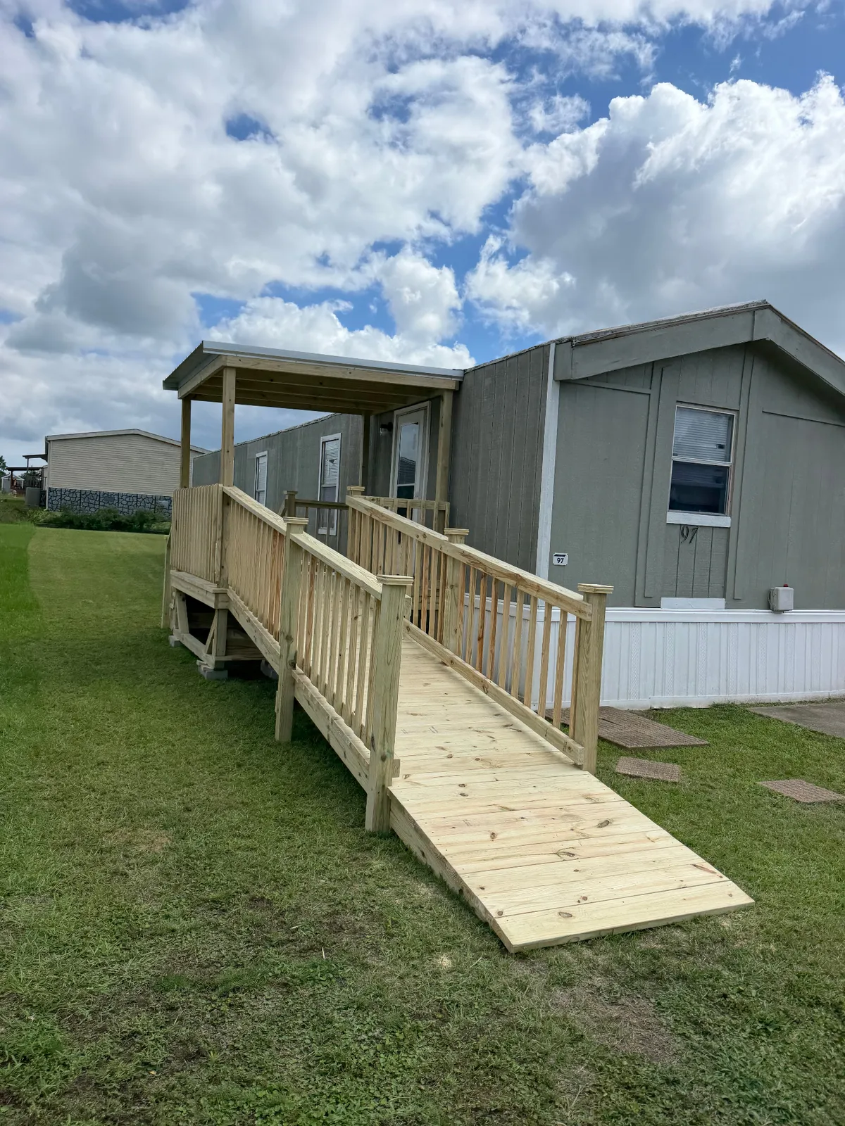 Portable 8x8 pressure treated deck with 4x16 ramp and single slope Galvalume roof on a manufactured home, built by BenchMark Decks in Tyler, Texas