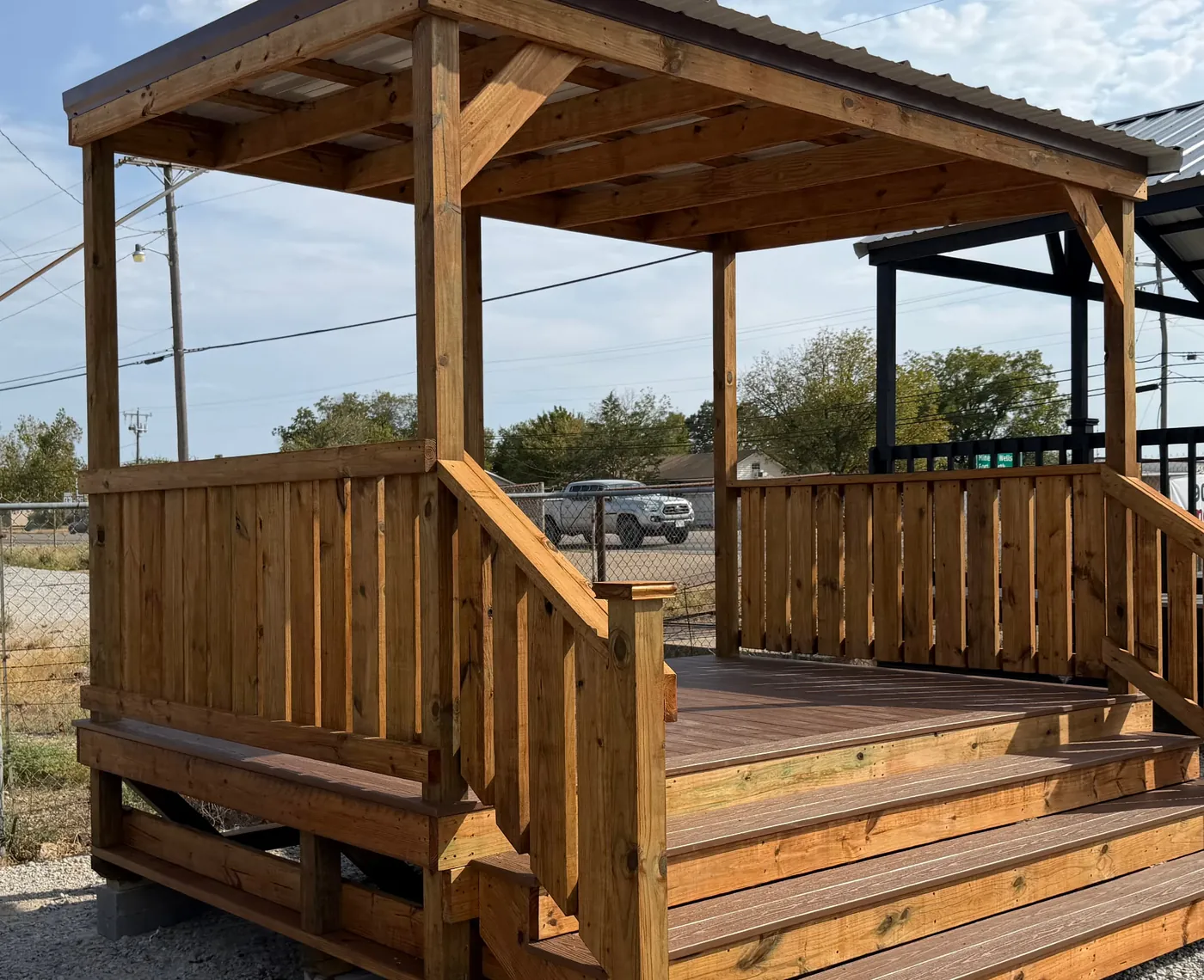Stained pressure-treated deck with covered pavilion roof, railing, and steps built by BenchMark Decks