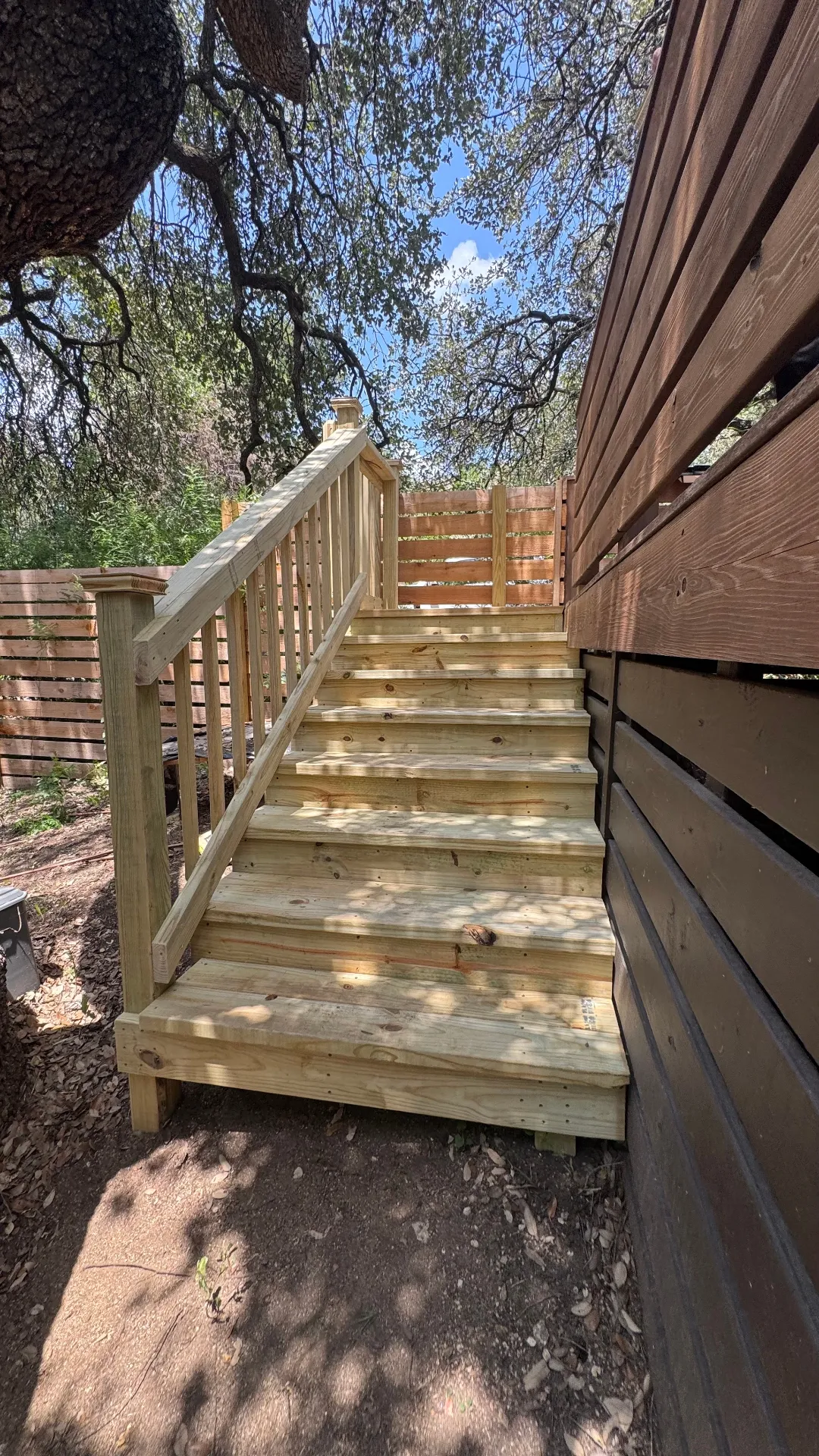 Solid pressure treated stairs with handrail beside a privacy fence and existing deck, built by BenchMark Decks in Austin, Texas
