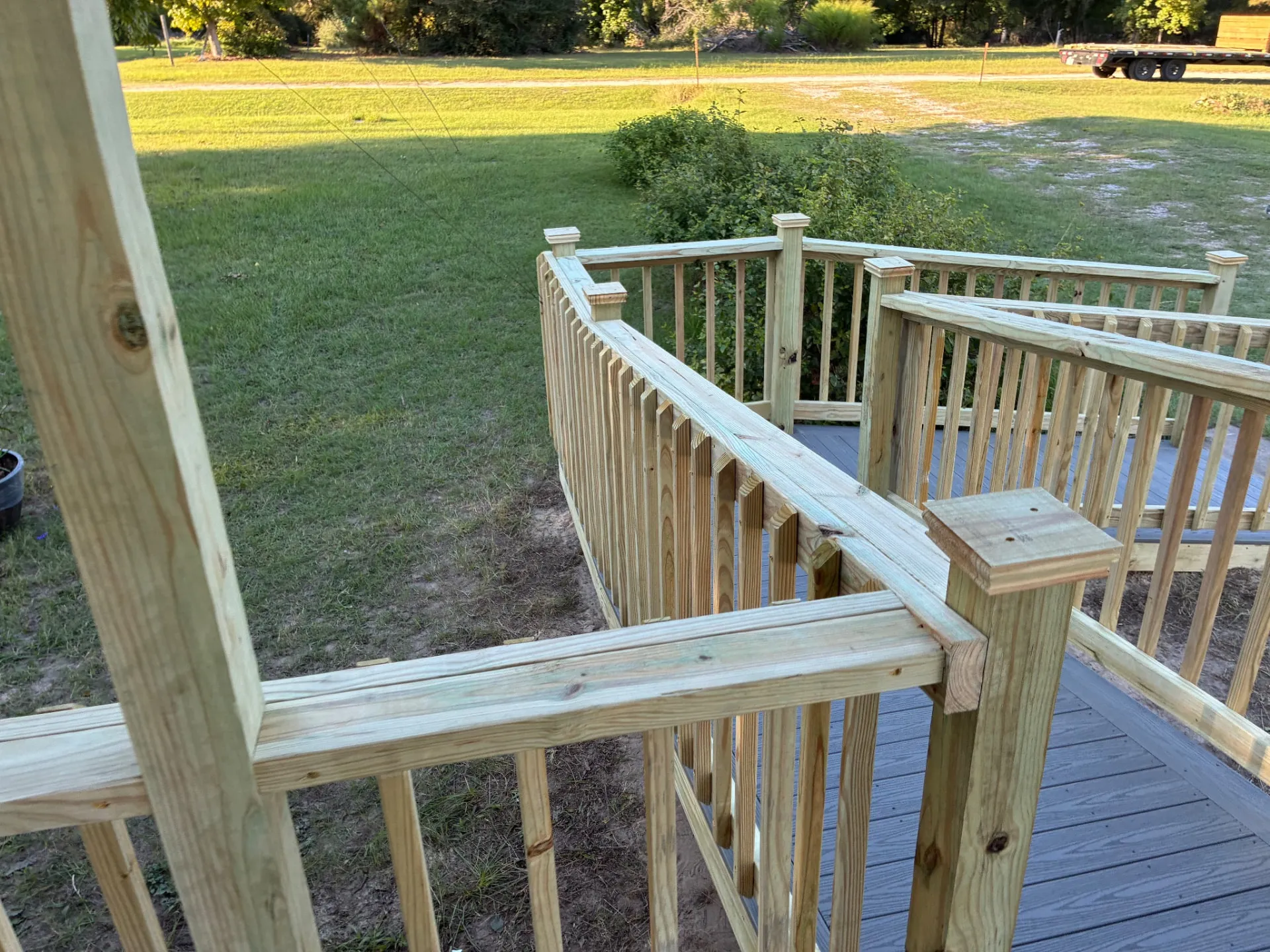 Treated wood railing and post caps around a composite ramp, built by BenchMark Decks in Trinity, Texas