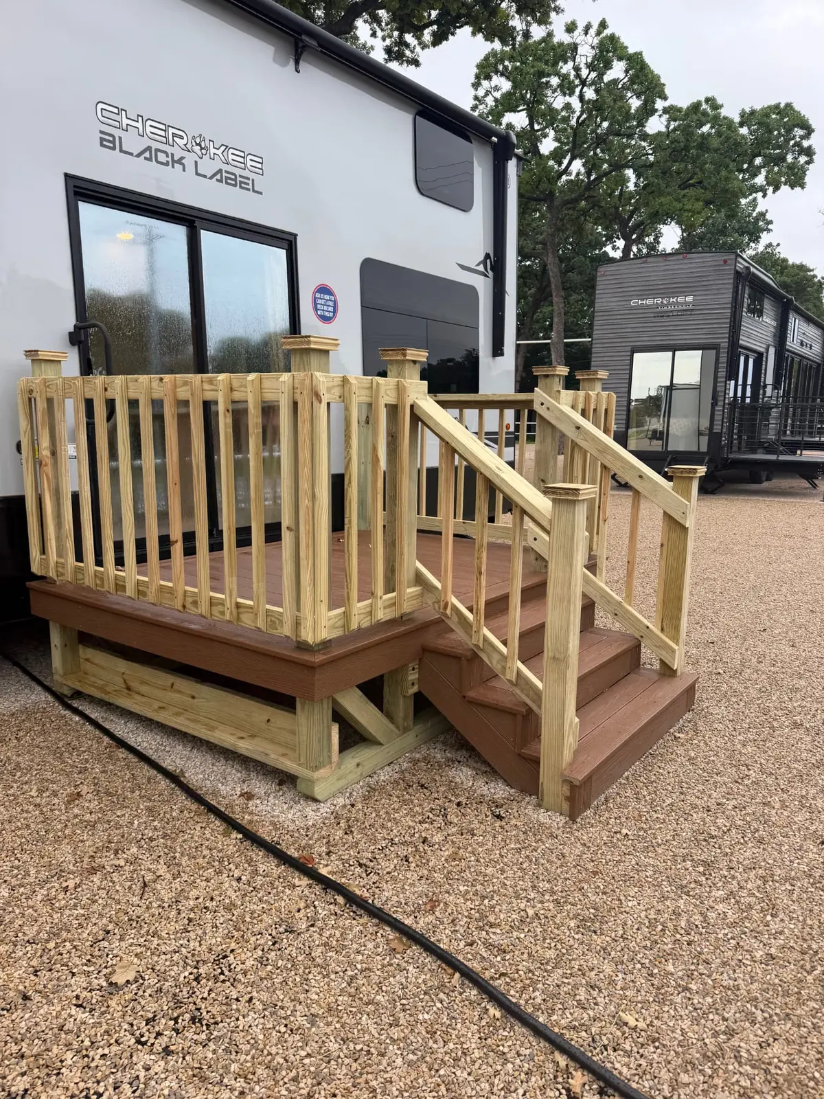 Composite RV deck with wood railing and stairs at an RV display lot