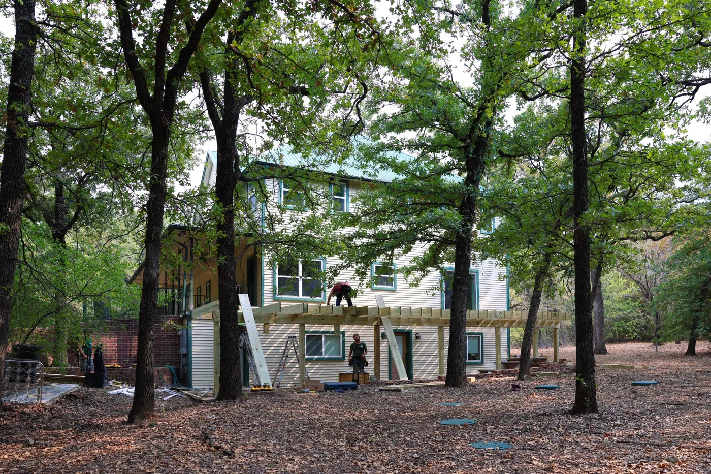 Wide view of Greg's Grandview, TX home with new deck framing going up under the oak trees