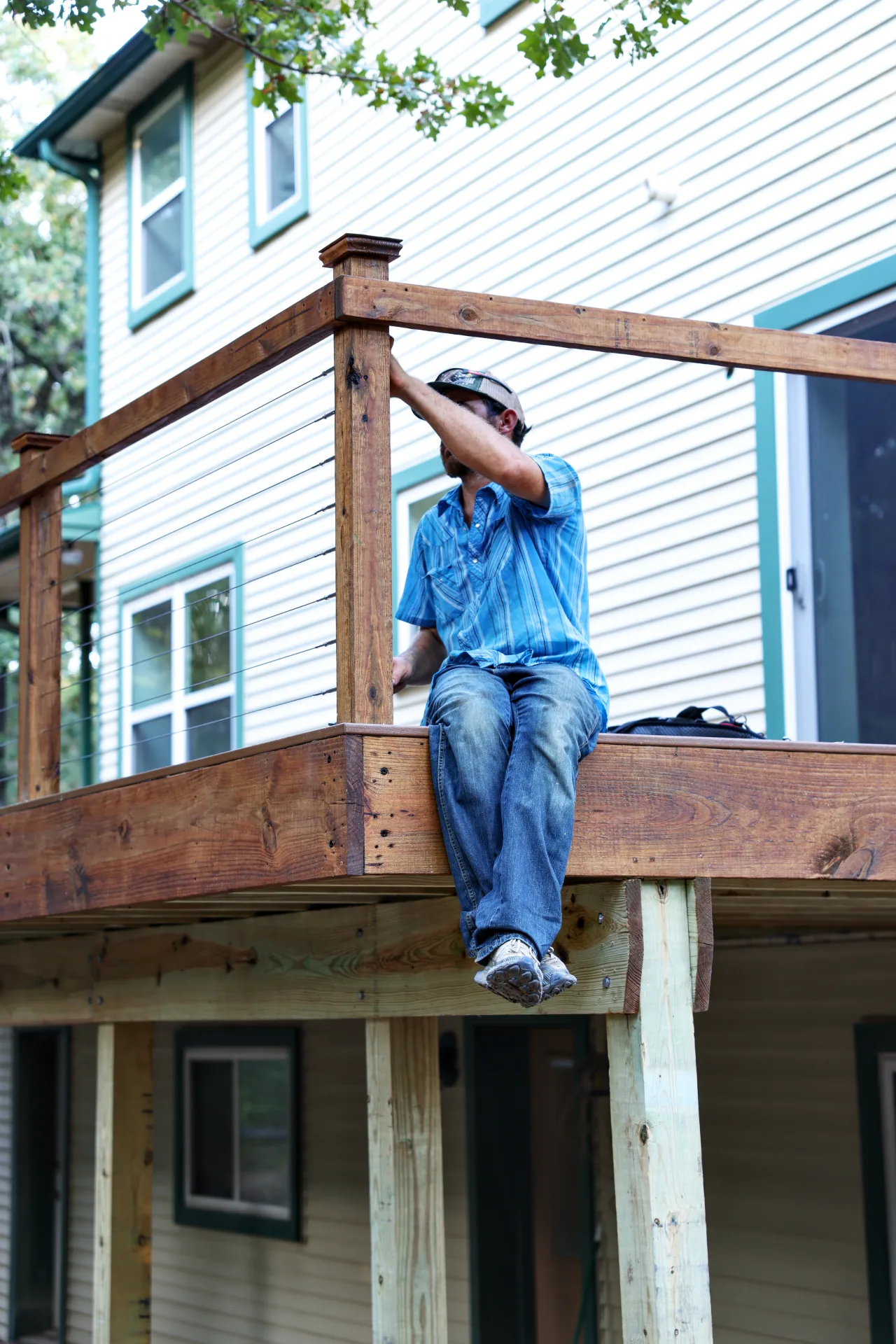 Benchmark Decks crew member installing cable railing on an elevated deck in Grandview, TX