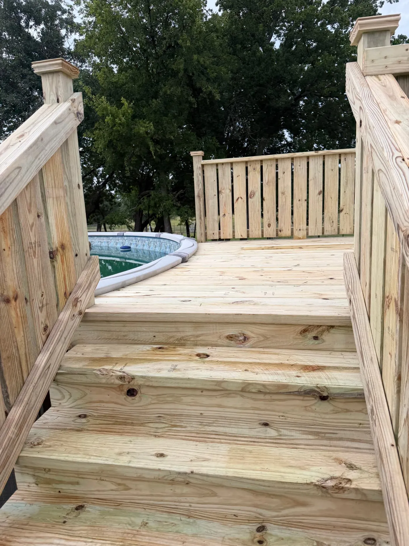 Pool deck stairs leading up to a curved above-ground pool surround