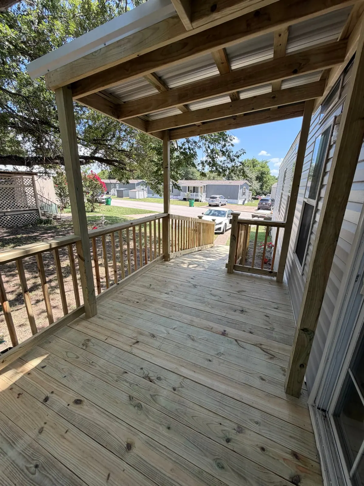 View along a covered mobile home porch deck with pressure-treated railing