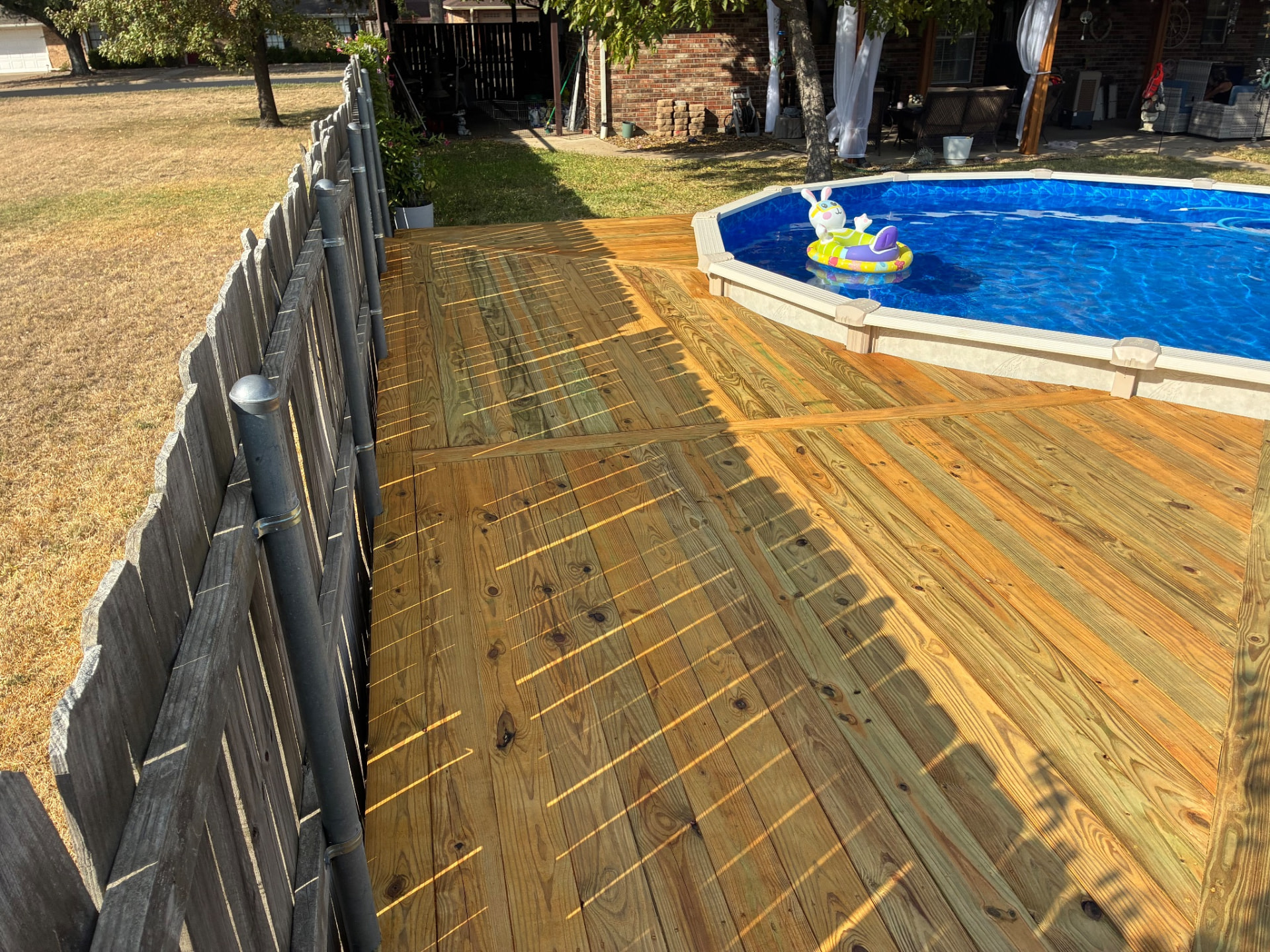 Angled deck sections with a divider board beside the pool, built by BenchMark Decks in Mabank, Texas