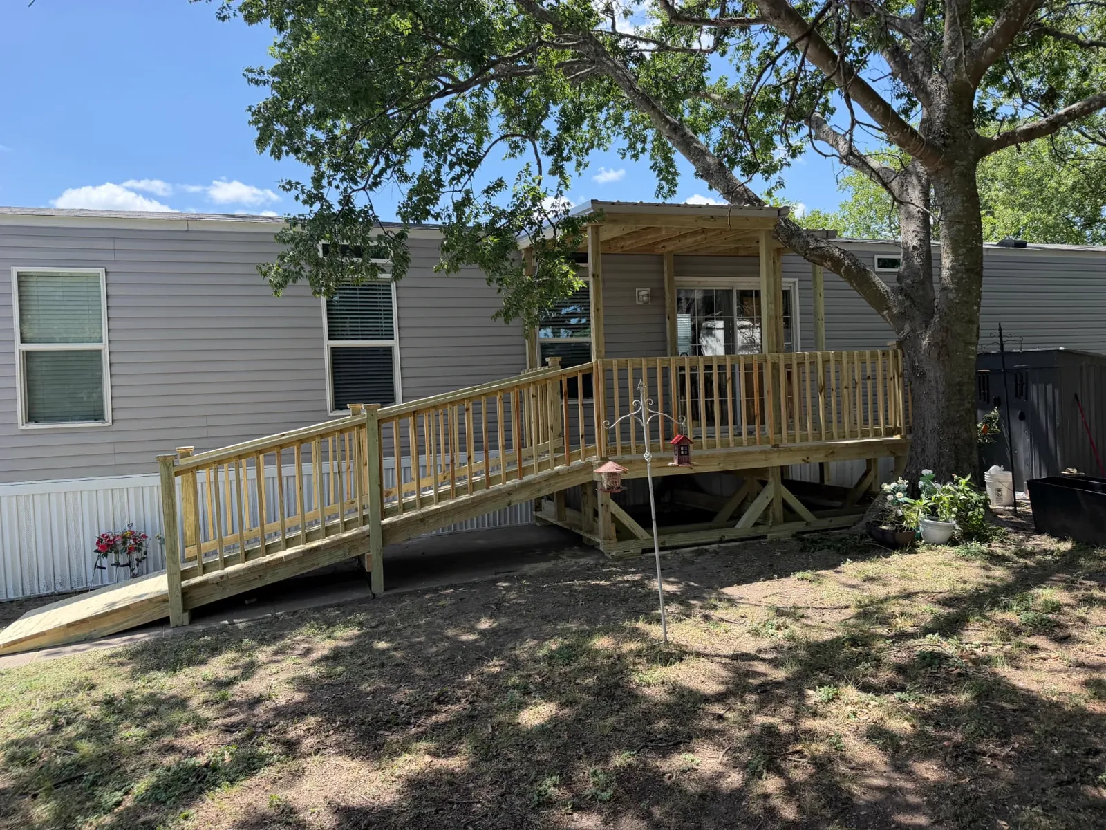 12x8 covered pressure treated deck with 4x16 ramp at the French doors of a manufactured home, built by BenchMark Decks in Waxahachie, Texas