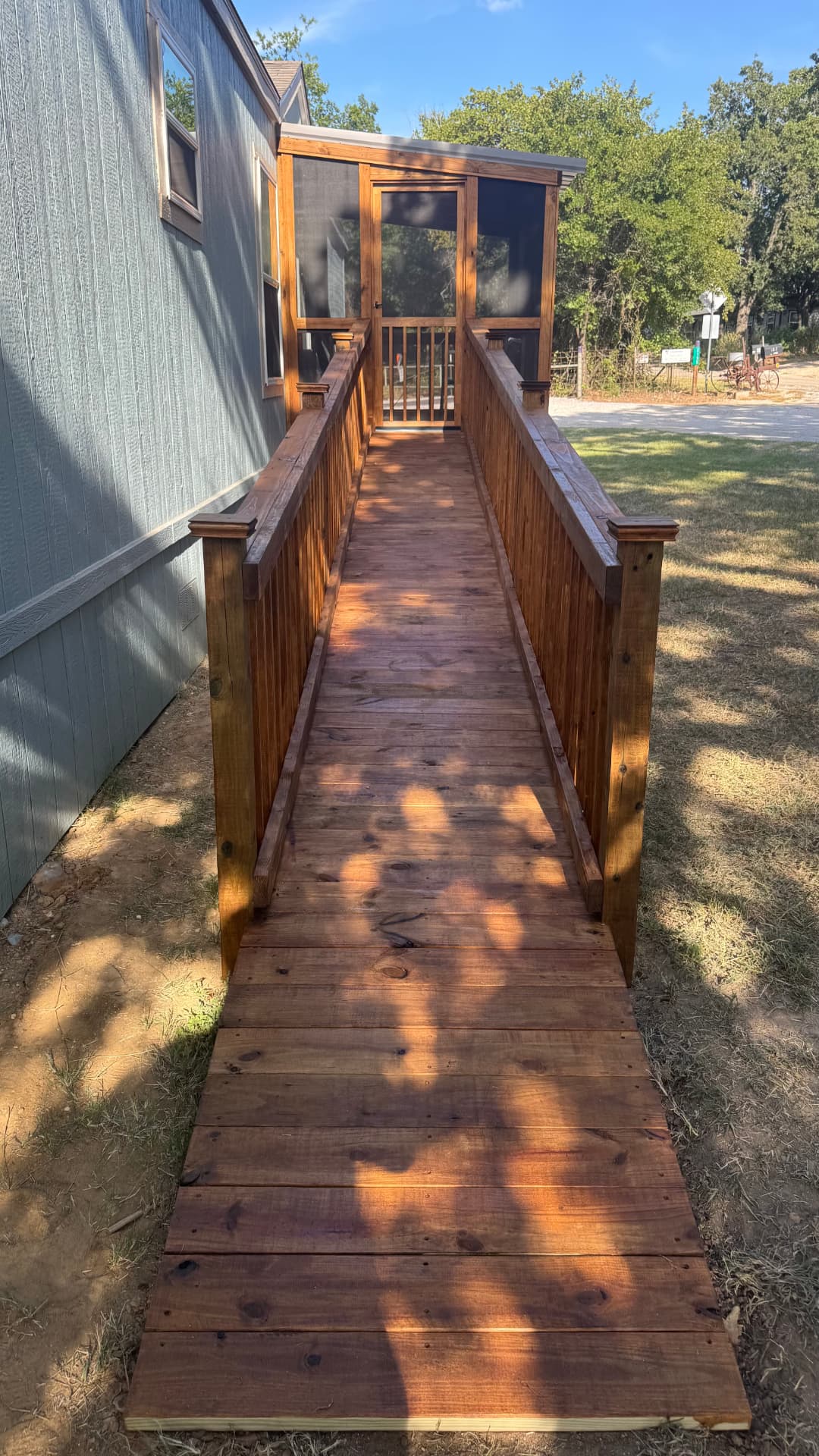 Stained wheelchair ramp leading to a screened porch on a mobile home