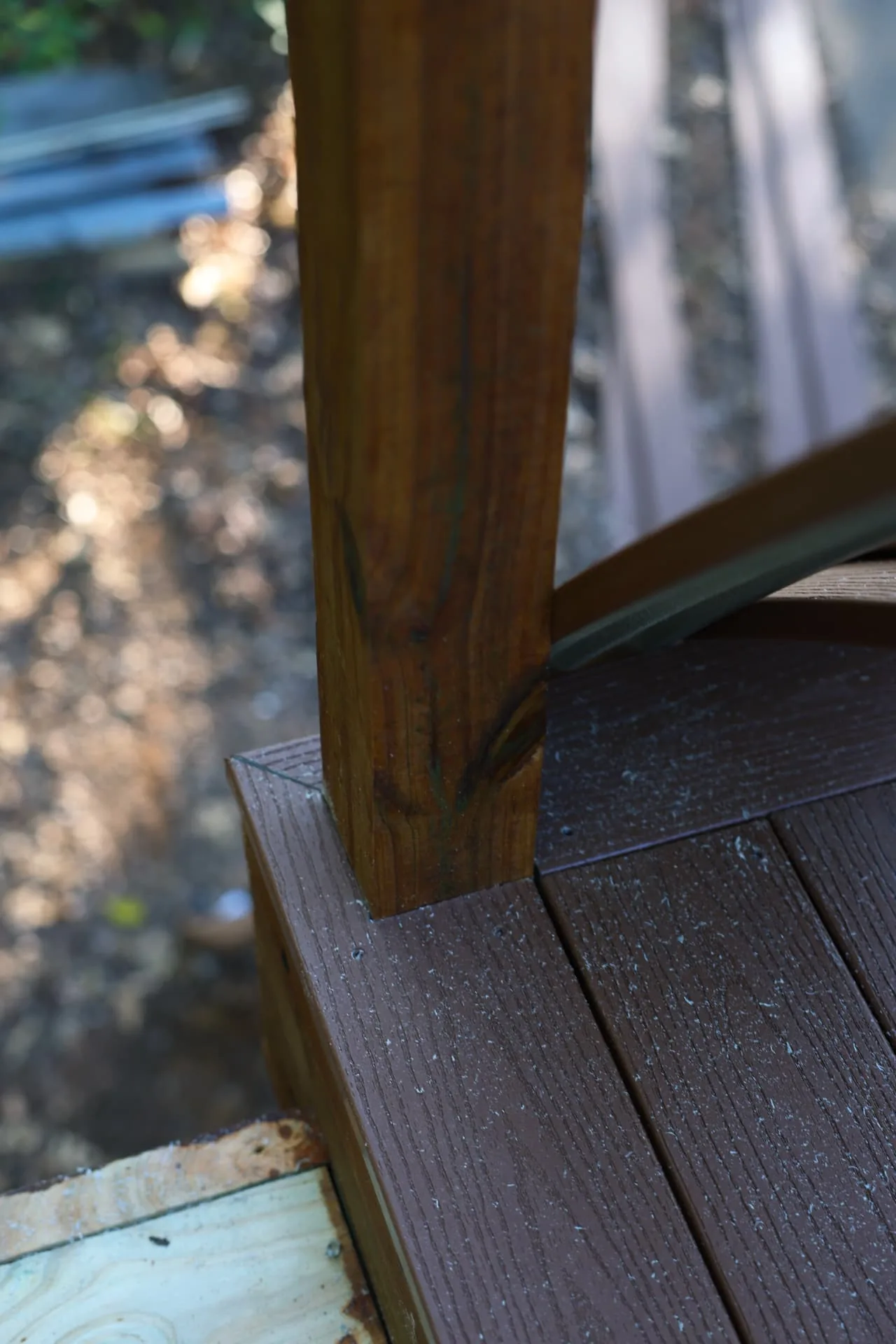 Composite deck board notched around a stained rail post with cable railing hardware