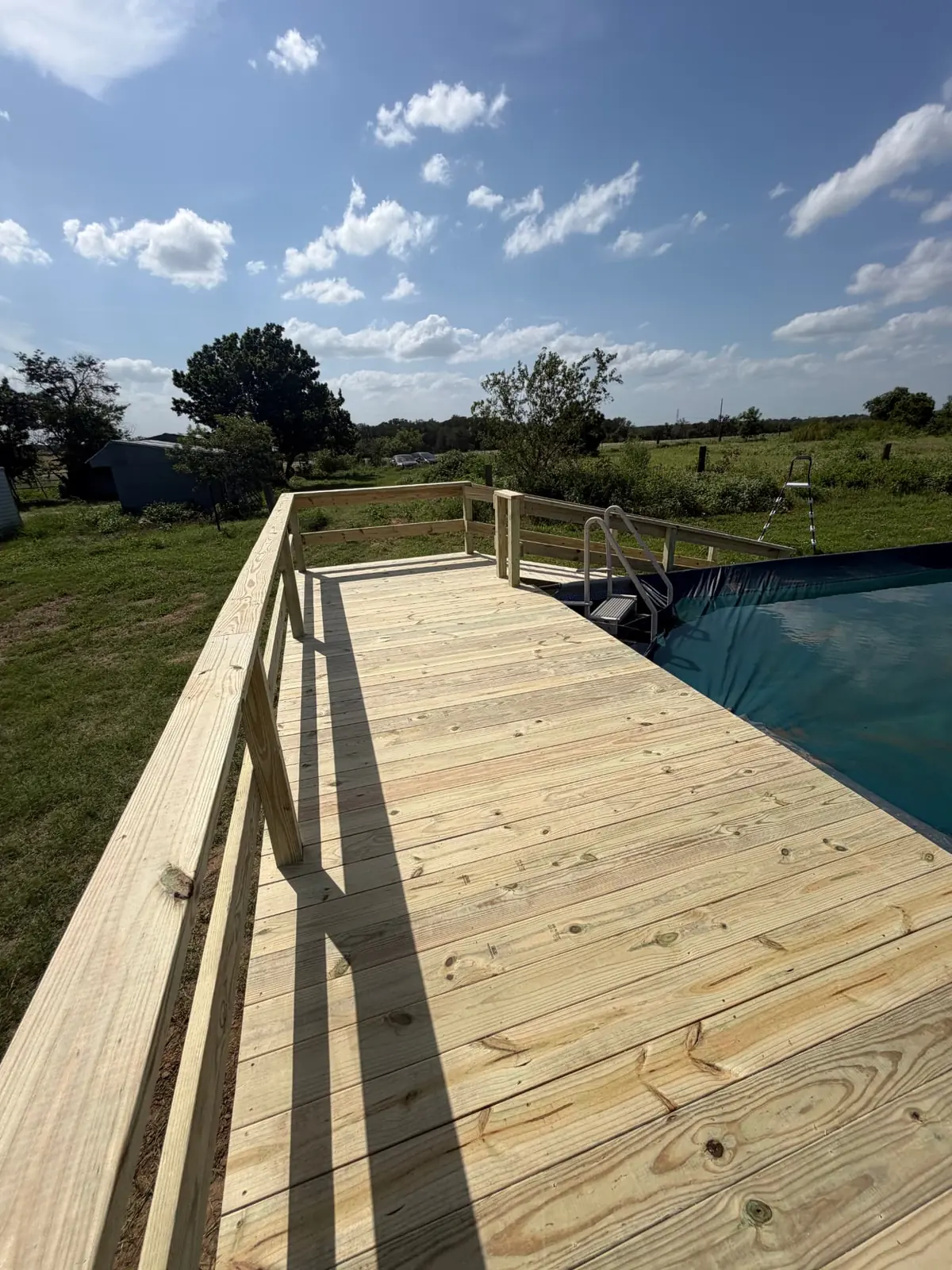 Long pool-side deck walkway with railing