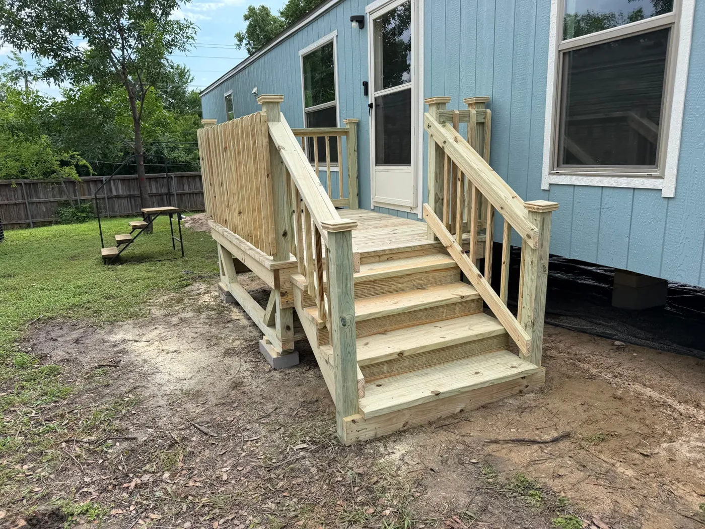 Mobile home deck with privacy wall, railing, and wide stairs