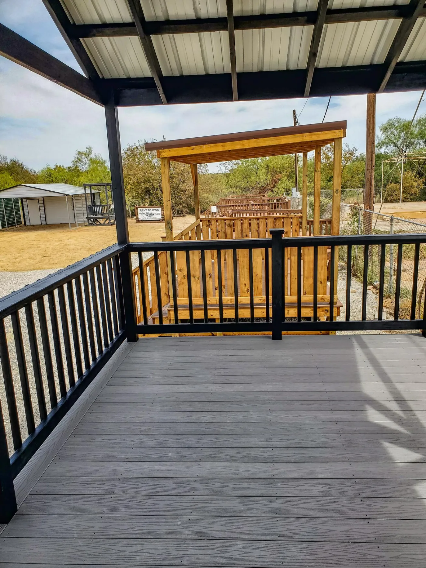 Gray composite decking under a covered deck with black railing