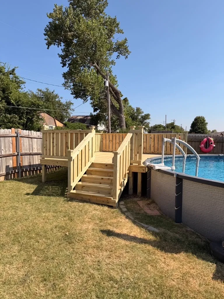 Treated wood above-ground pool deck with open pool side, stairs and railing with post caps, built by BenchMark Decks in Davis, Oklahoma