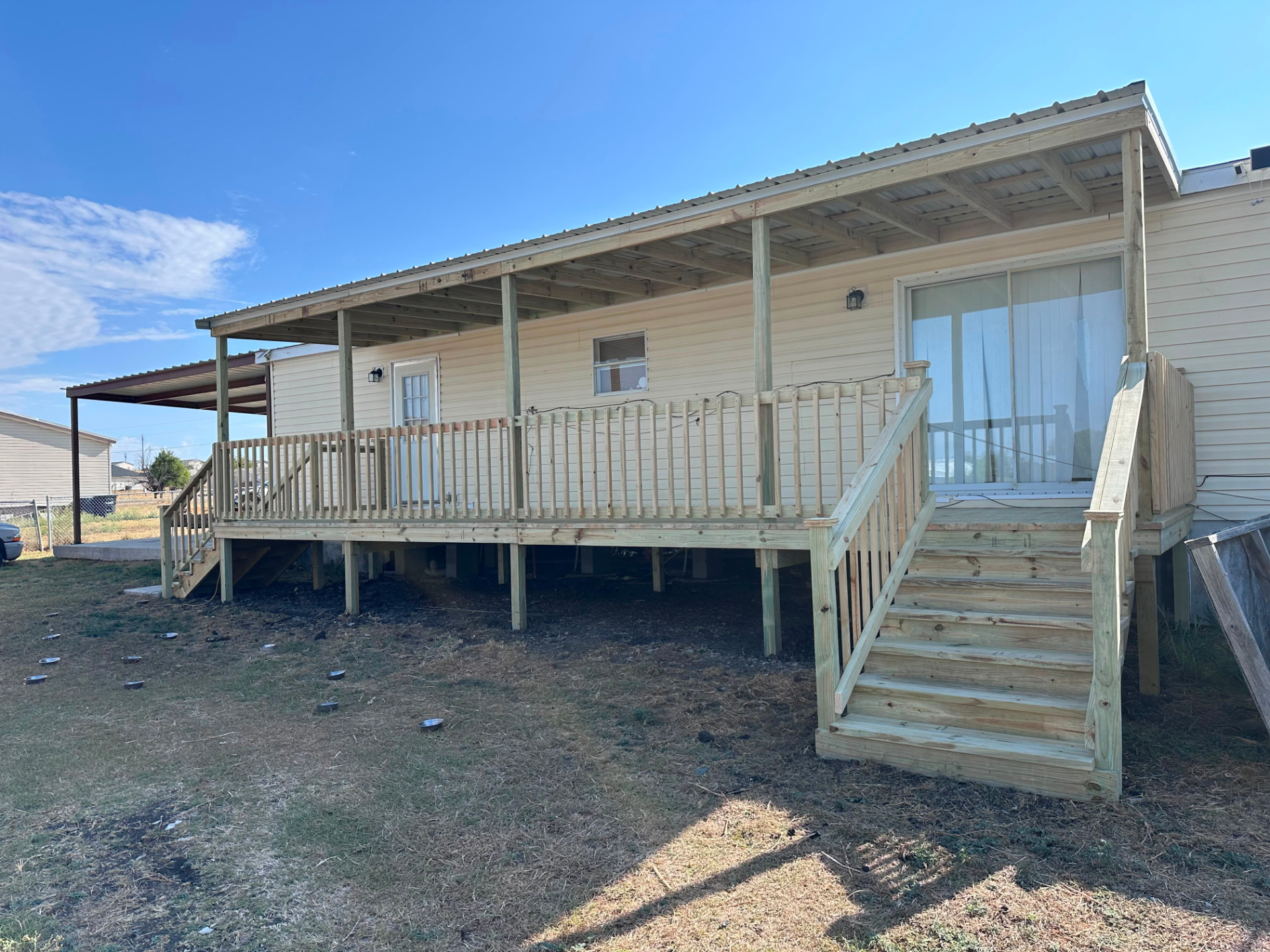 Completed covered deck with metal roof and wide stairs along the back of Violet's mobile home