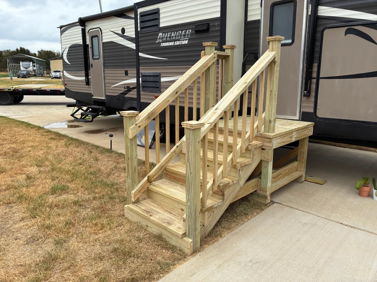 4x4 pressure treated RV entry deck with steps and wood railing beside a travel trailer, built by BenchMark Decks in Burleson, Texas