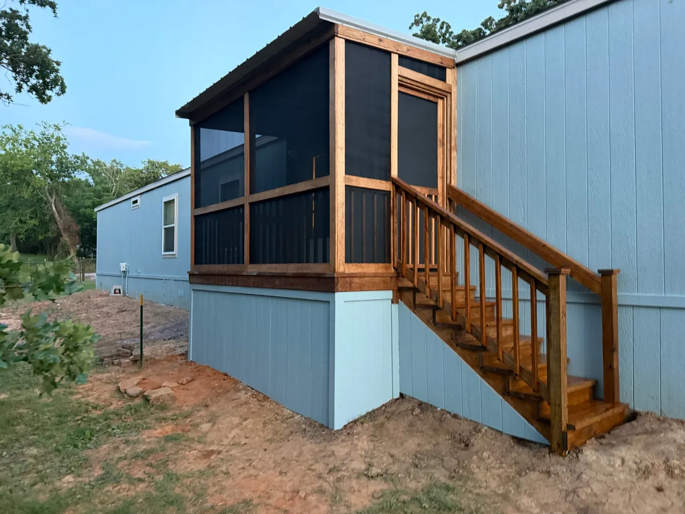 Stained screened-in porch addition on a mobile home with stairs
