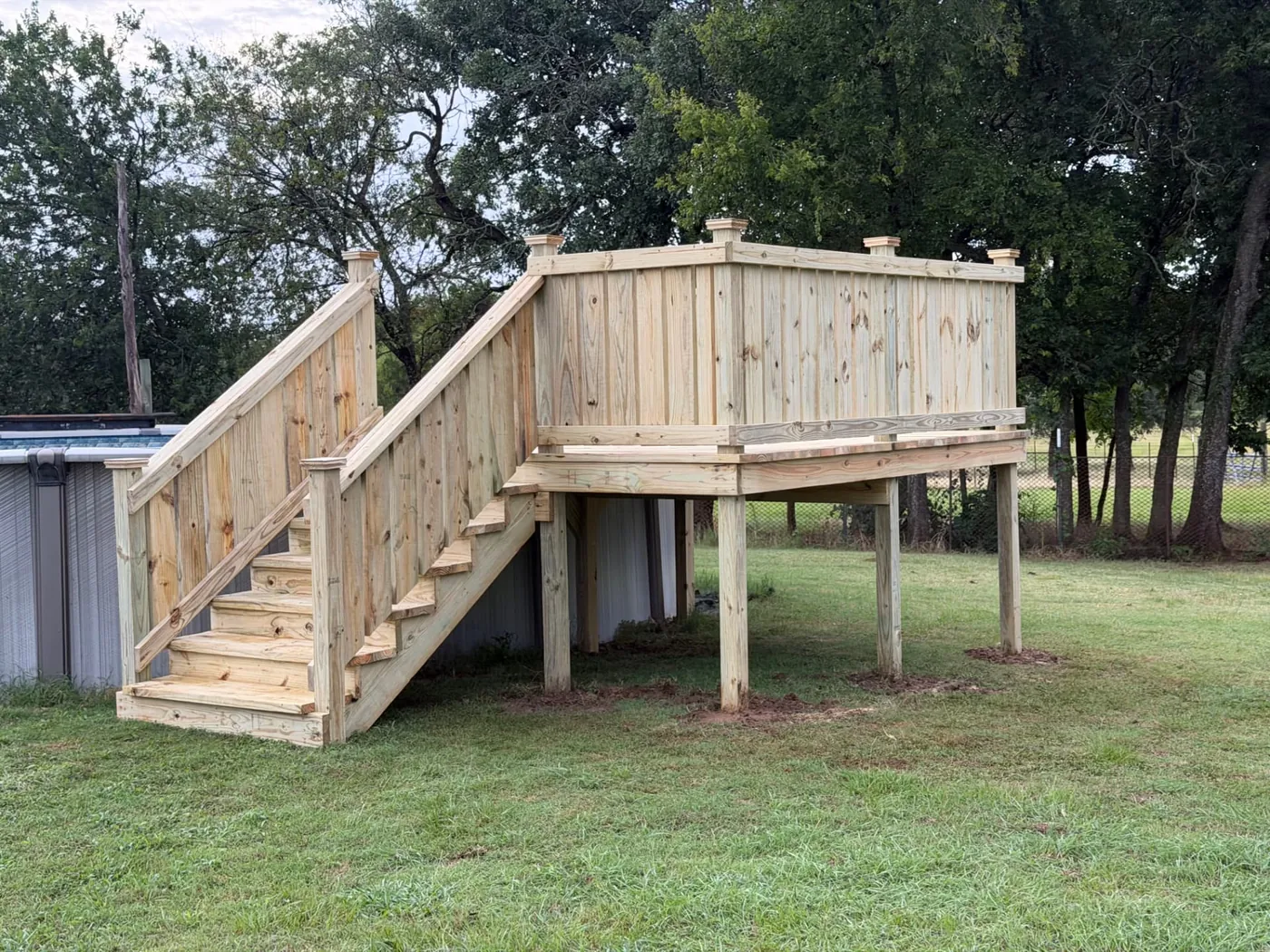 Tall above-ground pool deck with solid privacy skirting and stairs